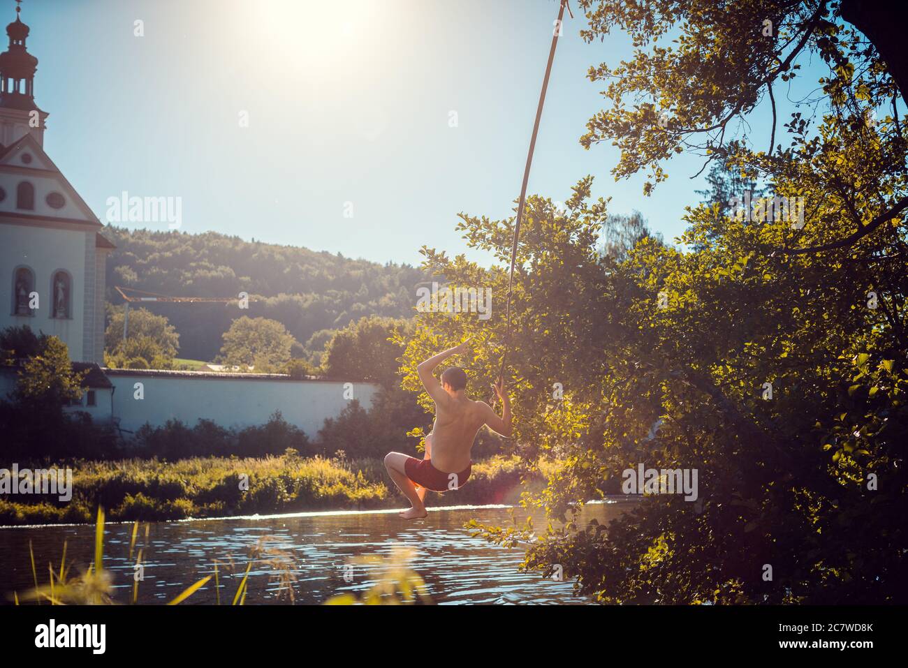 Mann schwingt auf einem Seil in das Wasser eines Flusses Stockfoto