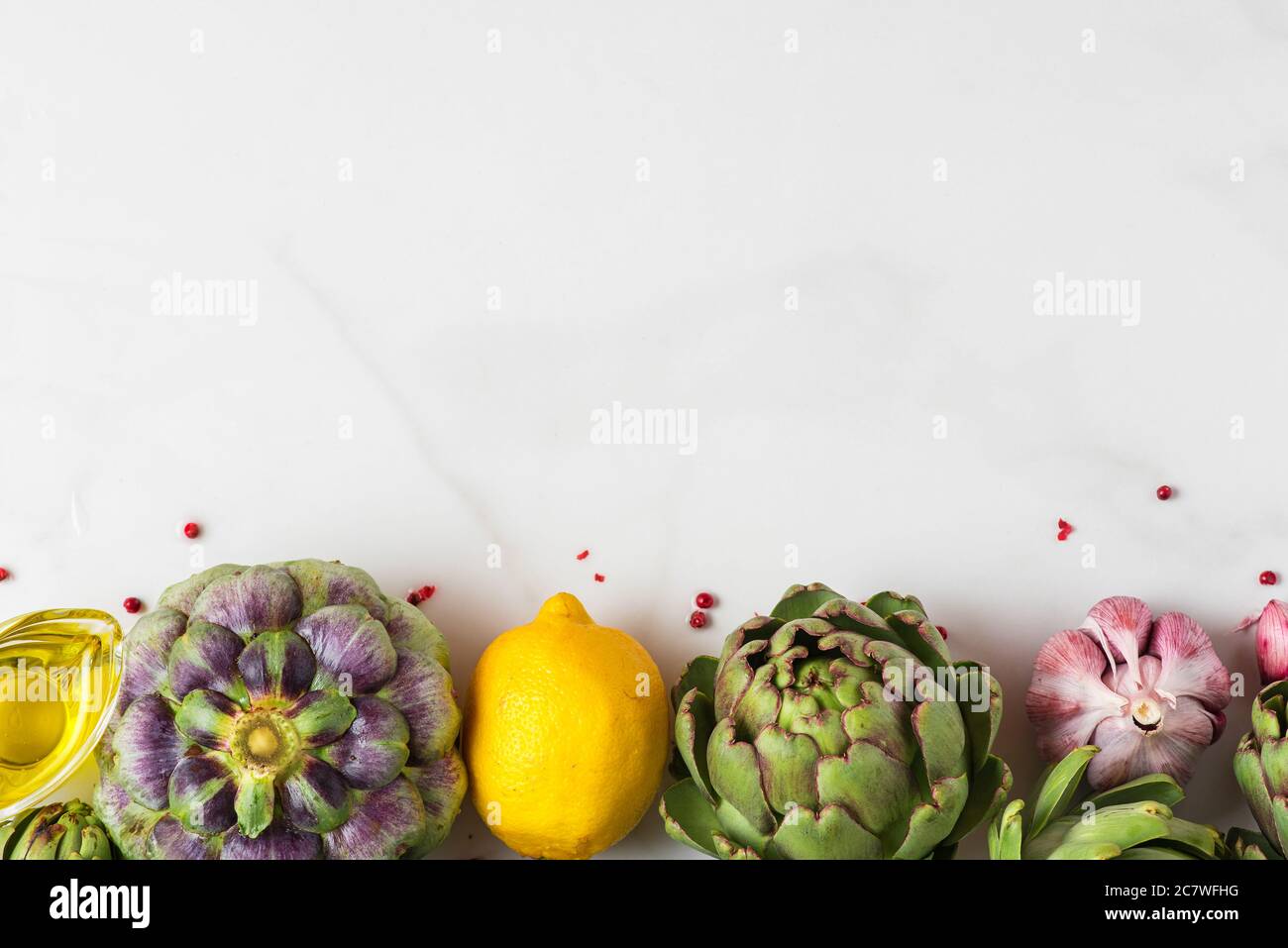 Frische reife Artischocken, Zitrone und Knoblauch mit Olivenöl und Pfeffer auf weißem Marmortisch. Gesundes veganes Lebensmittelkonzept. Flach liegend, Draufsicht mit Kopierraster Stockfoto