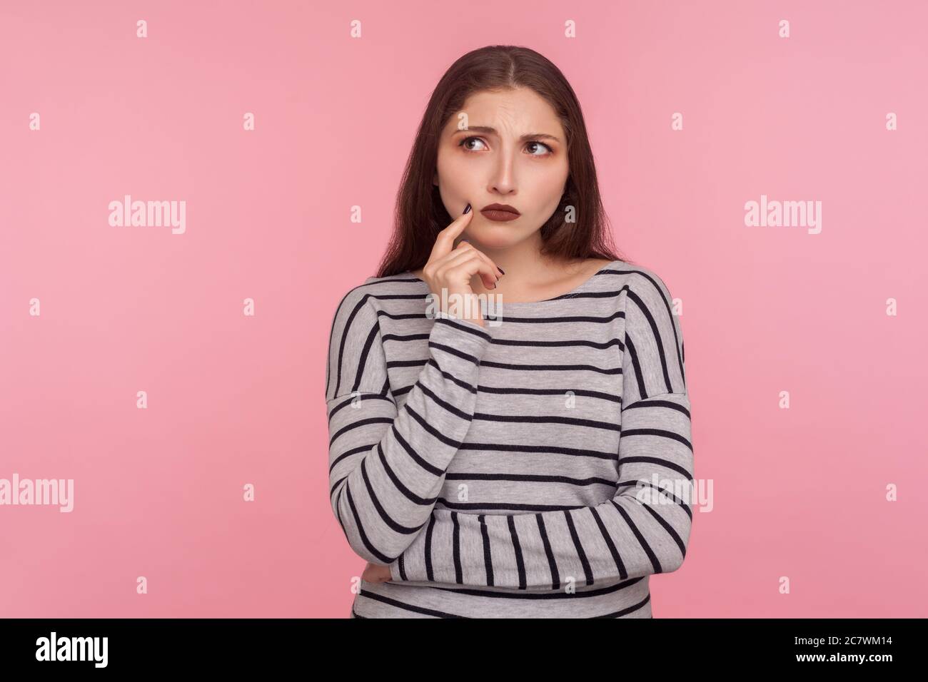 Porträt der besorgt nachdenklichen jungen Frau im gestreiften Sweatshirt berühren Kinn beim Nachdenken über Problem, nicht sicher, Zweifel in schwierigen Frage Stockfoto