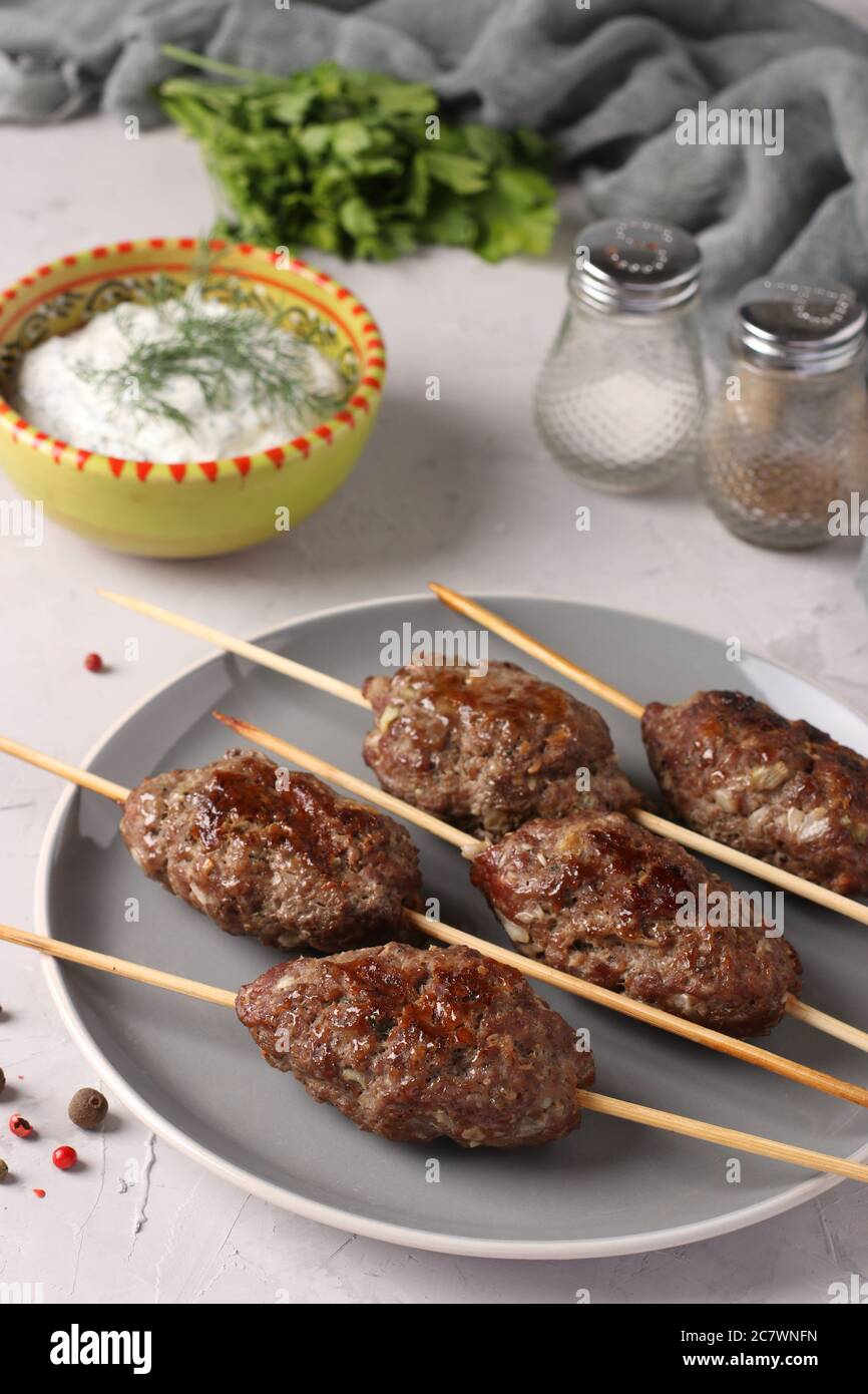 Kofta Kebab auf Holzspieße auf einem Teller und Sauce auf dem Tisch, traditionelle Gericht der arabischen Küche, gegrilltes Hackfleisch Schisch Kebab Stockfoto