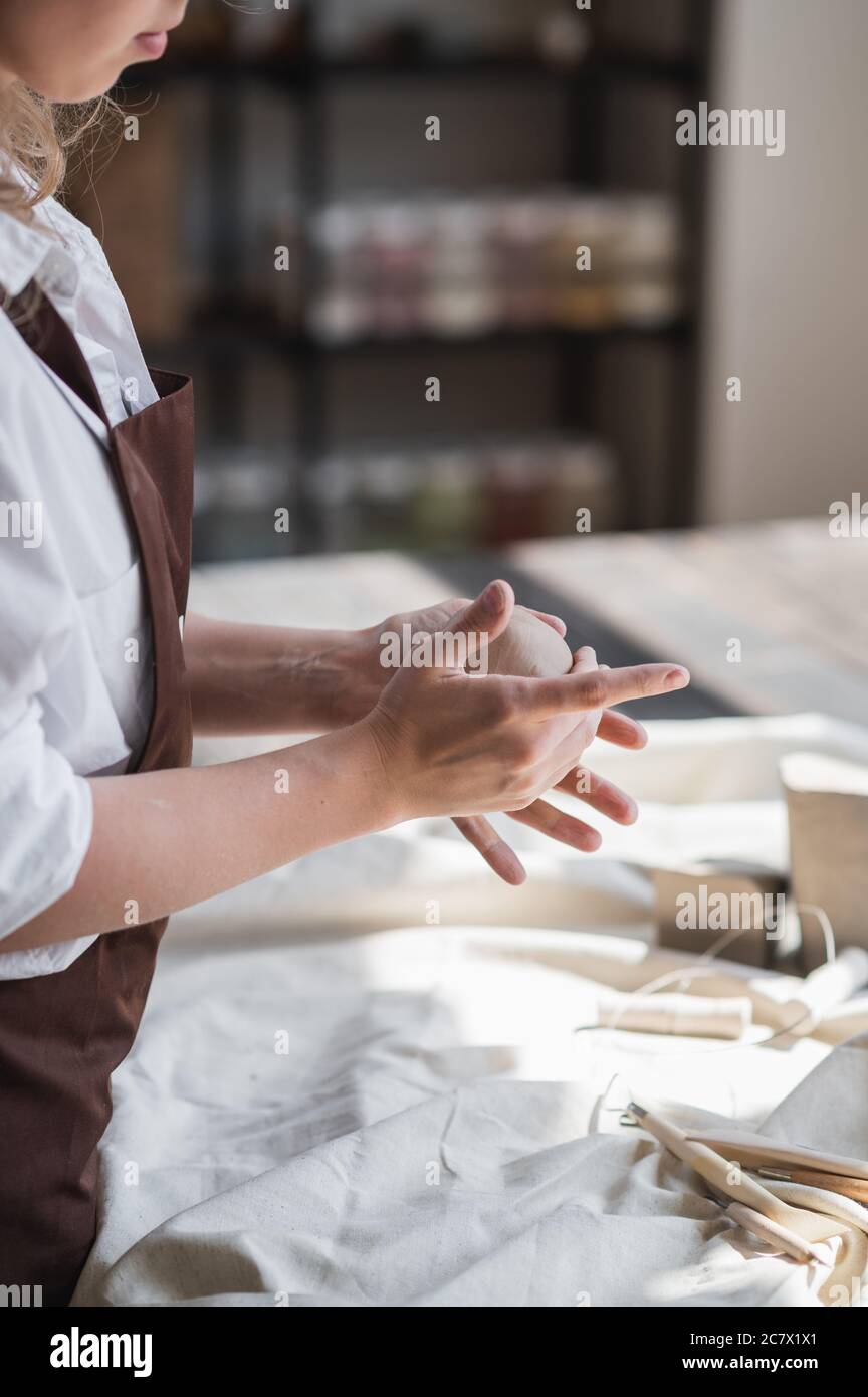 Weibliche Töpferin formt ein Stück Ton am Tisch. Frau, die Keramik-Element. Töpferarbeiten, handgemachte und kreative Fähigkeiten im Kunststudio. Stockfoto