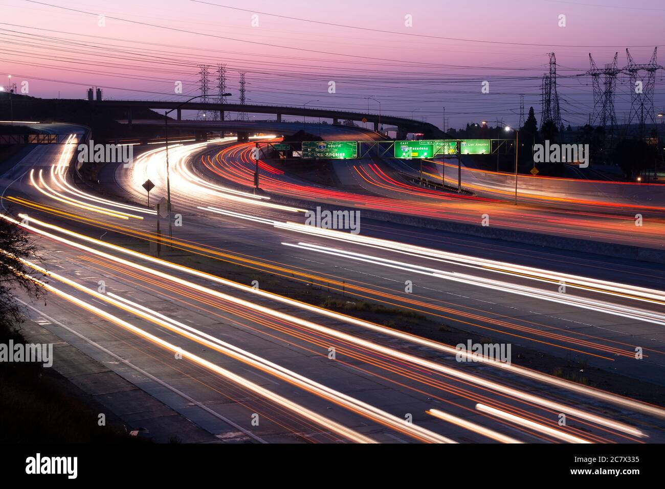 Verschwommene Scheinwerfer und Rücklichter vorbeifahrenden Autos an der Kreuzung der Interstate 5 und 210 im San Fernando Valley bei Sonnenaufgang Stockfoto