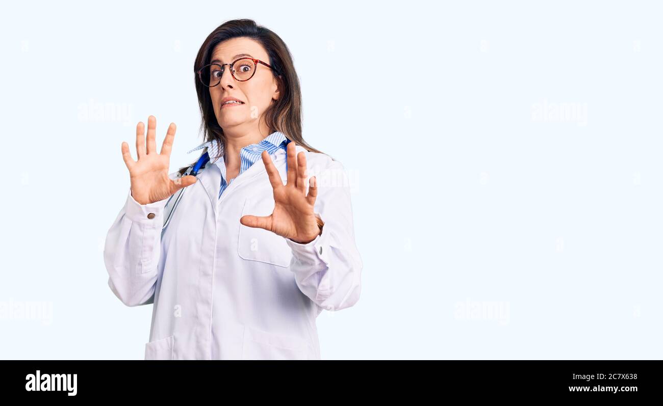 Junge schöne Frau trägt Arzt Stethoskop und Brille Angst und erschrocken vor Angst Ausdruck Stop Geste mit Händen, schreien im Schock. Pan Stockfoto