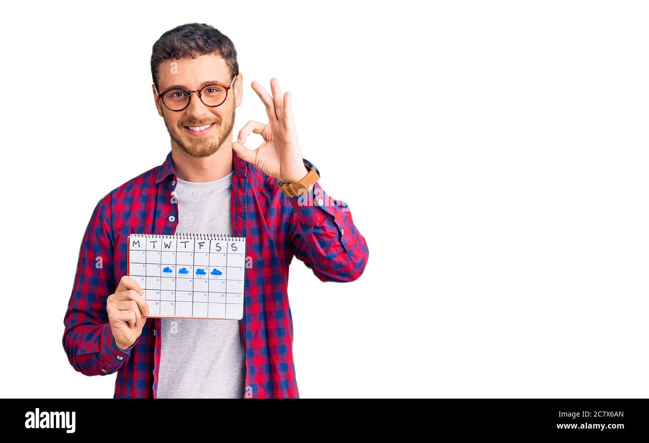 Schöner junger Mann mit Bär halten Reisekalender tun ok Zeichen mit Fingern, lächelnd freundlich gestikulieren ausgezeichnete Symbol Stockfoto