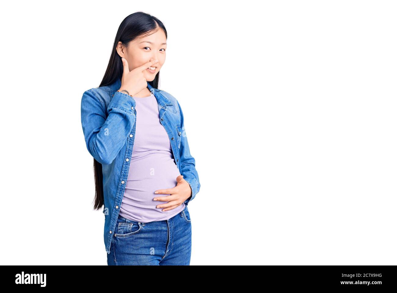 Junge schöne chinesische Frau schwanger erwartet Baby zeigt mit der Hand Finger auf Gesicht und Nase, lächelnd fröhlich. Beauty-Konzept Stockfoto