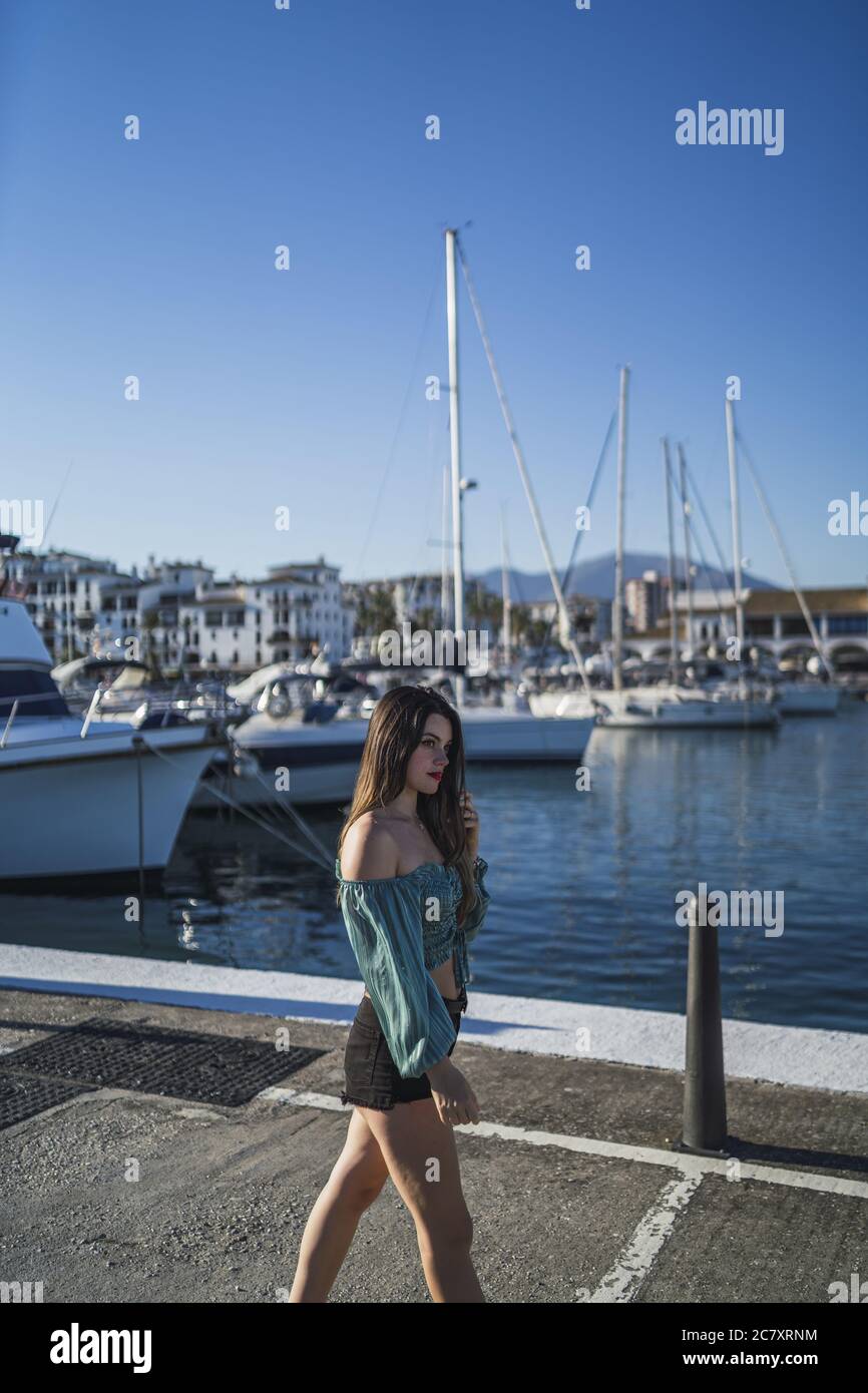 Flacher Fokus einer jungen Frau, die Shorts trägt, umgeben von Das Meer und Boote unter dem Sonnenlicht Stockfoto