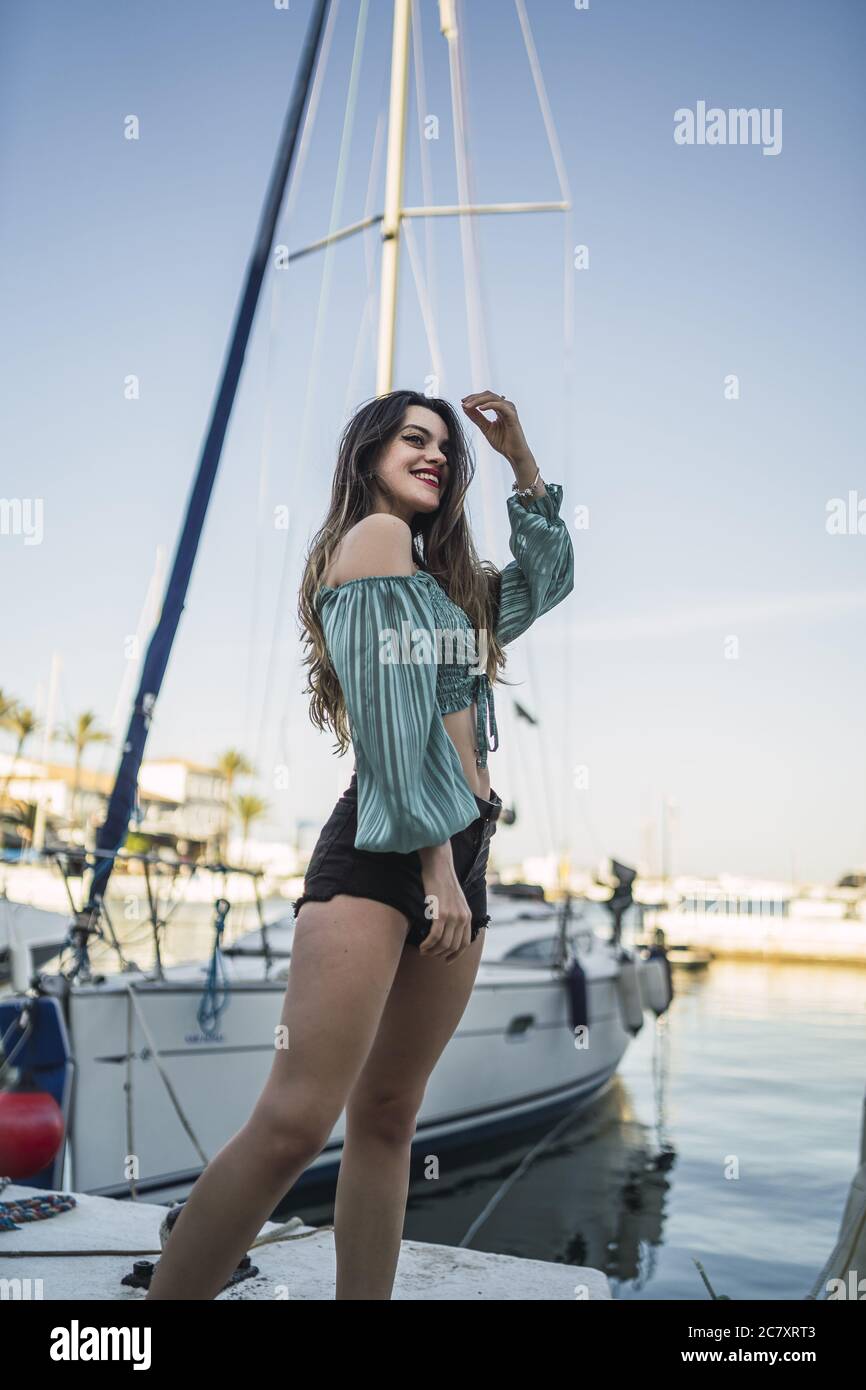 Flacher Fokus einer jungen Frau, die Shorts trägt, umgeben von Das Meer und Boote unter dem Sonnenlicht Stockfoto