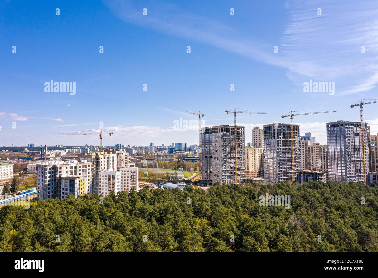 Hochhaus-Wohngebäude Baustelle mit Arbeitskränen gegen blauen Himmel. Luftaufnahme von fliegender Drohne Stockfoto