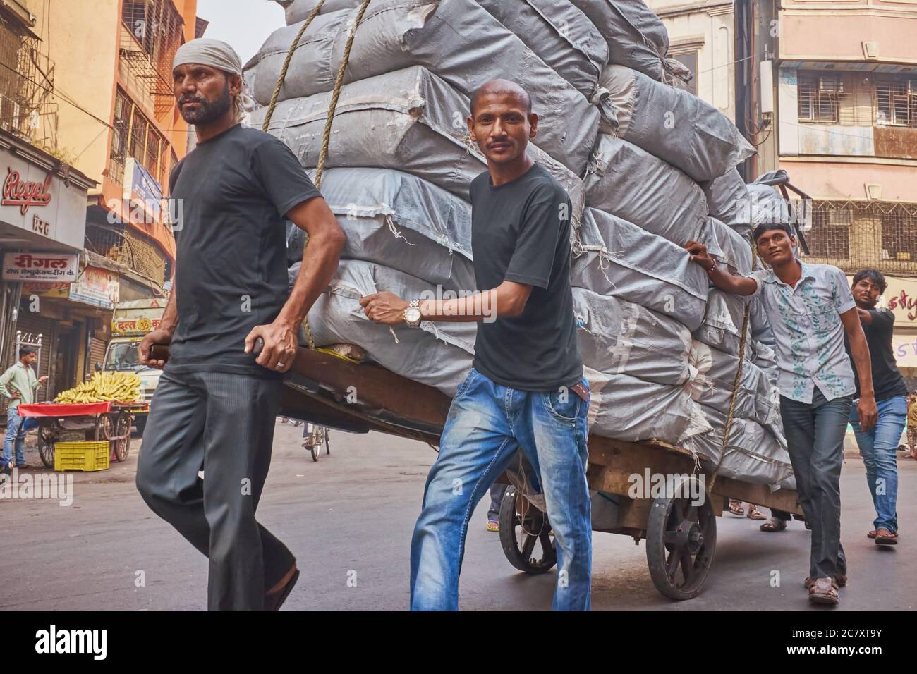 Ein Handwagen voller Stoffballen, der von vier Männern entlang der Kalbadevi Road, einem Textilhandelsgebiet im Bhuleshwar-Gebiet Mumbai, Indien, transportiert wurde Stockfoto