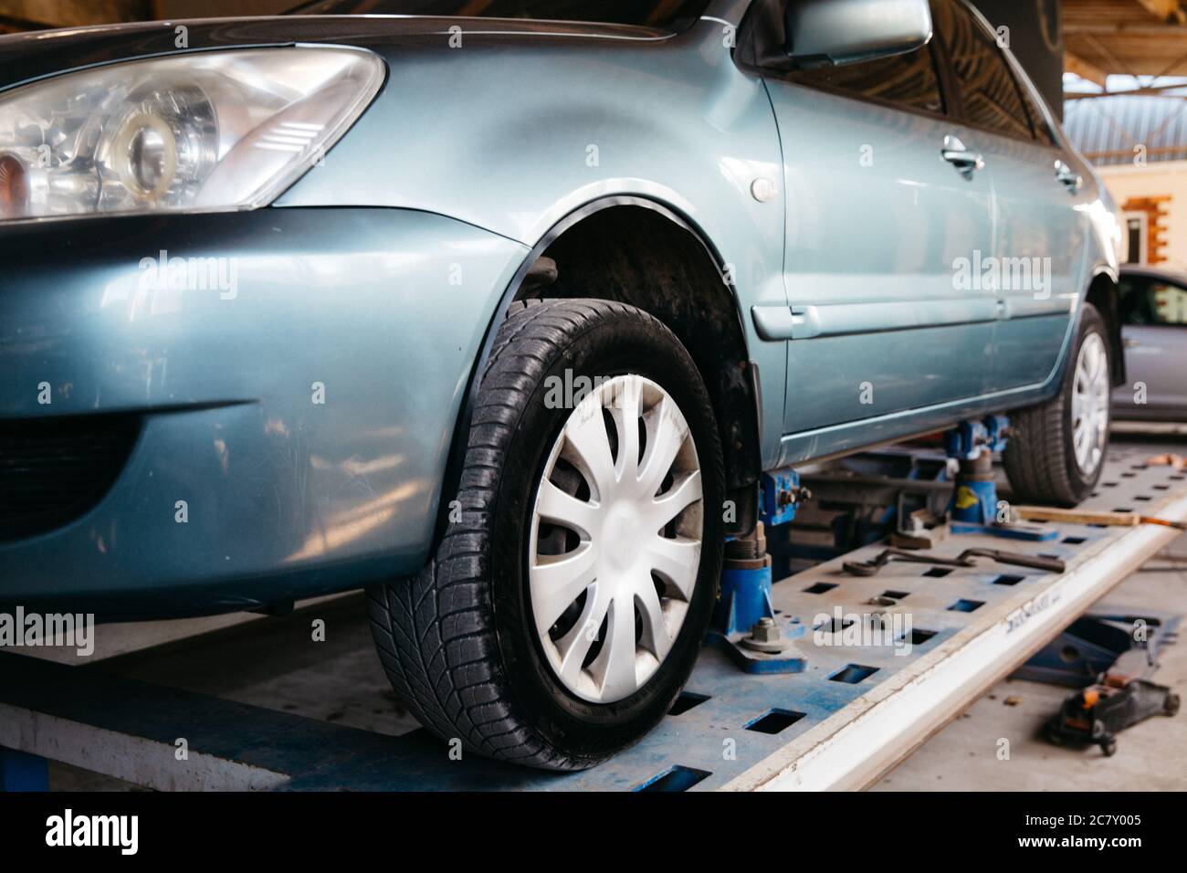 Ein blaues Auto wird zur Reparatur in einem Autoservice auf einen Aufzug gehoben. Stockfoto
