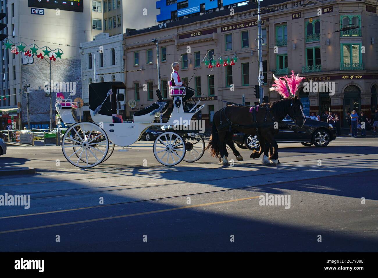 Melbourne, VIC / Australien - Dez 23 2018: Zwei schwarze Pferde mit rosa Ornamenten ziehen weiße Kutsche Stockfoto