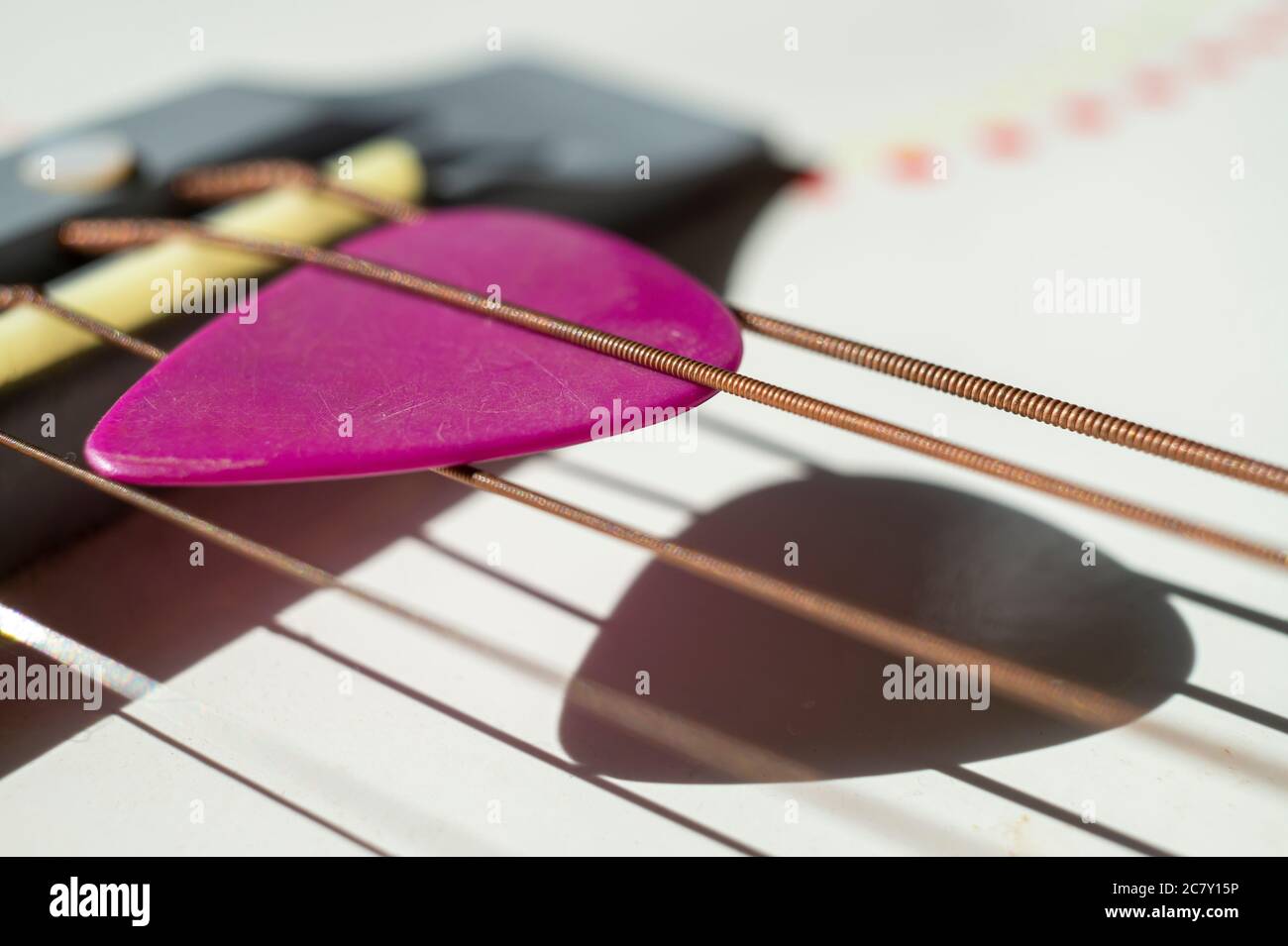 Bunte rosa Plektrum in Gitarre Saiten in einer Nahaufnahme schrägen Winkel  Ansicht in einem Musik-und Unterhaltungskonzept Stockfotografie - Alamy
