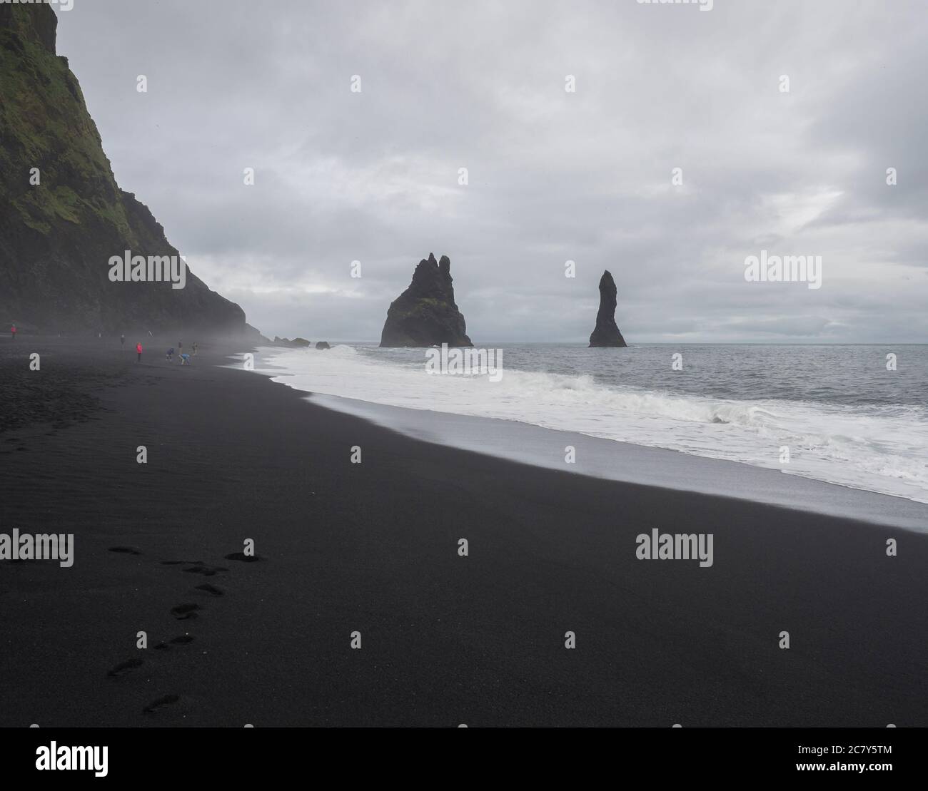 Basalt Felsformationen Troll Zehen auf schwarzem Sandstrand reynisfjara mit Gruppe von bunten Touristen Menschen, Nebel und launischen Himmel, monochromatischen Look Stockfoto