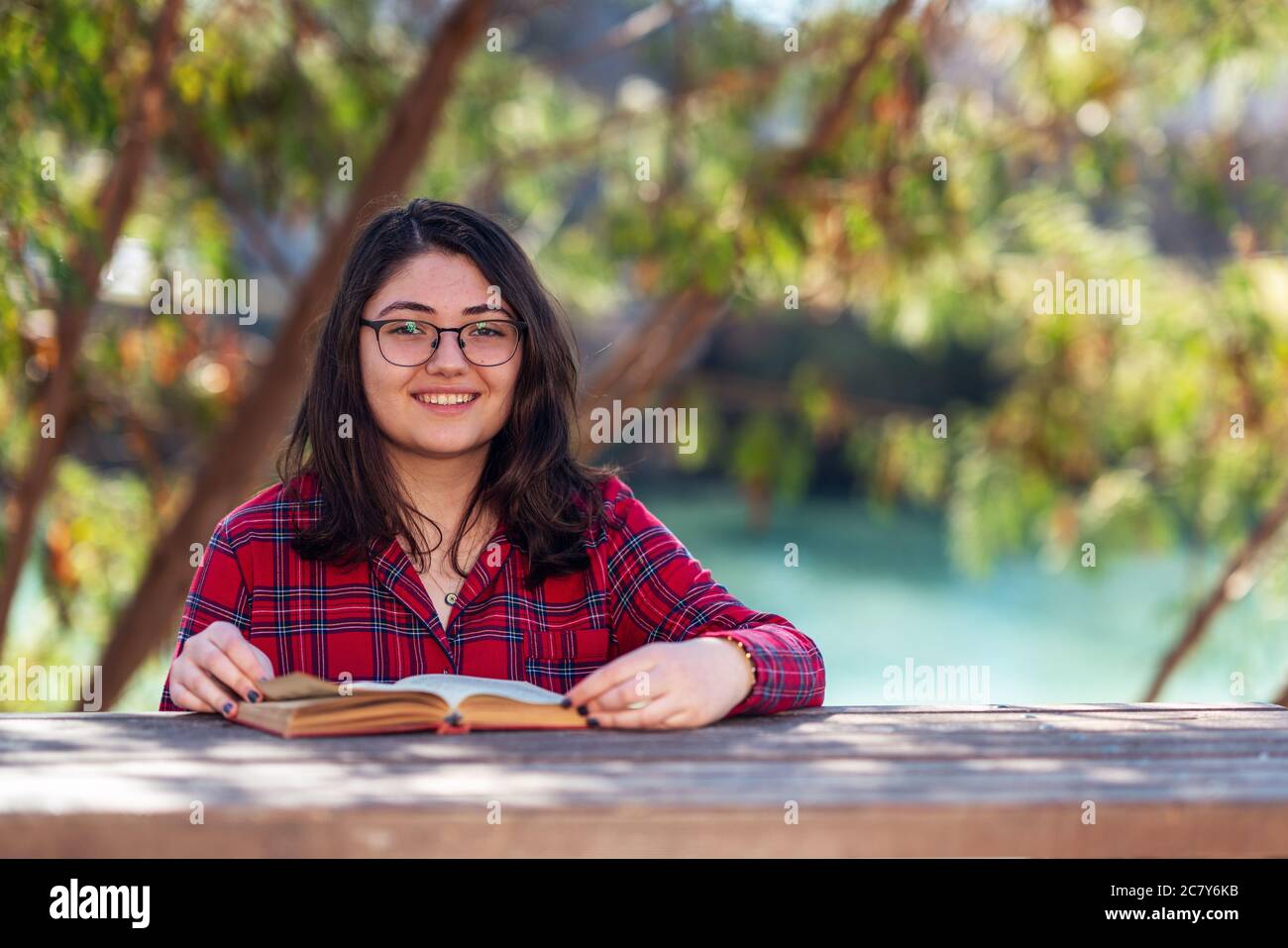 Intellektuelles junges Mädchen, das in einem Park sitzt und Buch liest oder mit Büchern studiert. Hochwertige Fotos Stockfoto
