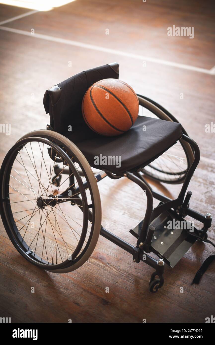Basketball und Rollstuhl in einsamer Atmosphäre, im Konzept Enttäuschung, Verletzung, Entmutigung, Verzweiflung Stockfoto