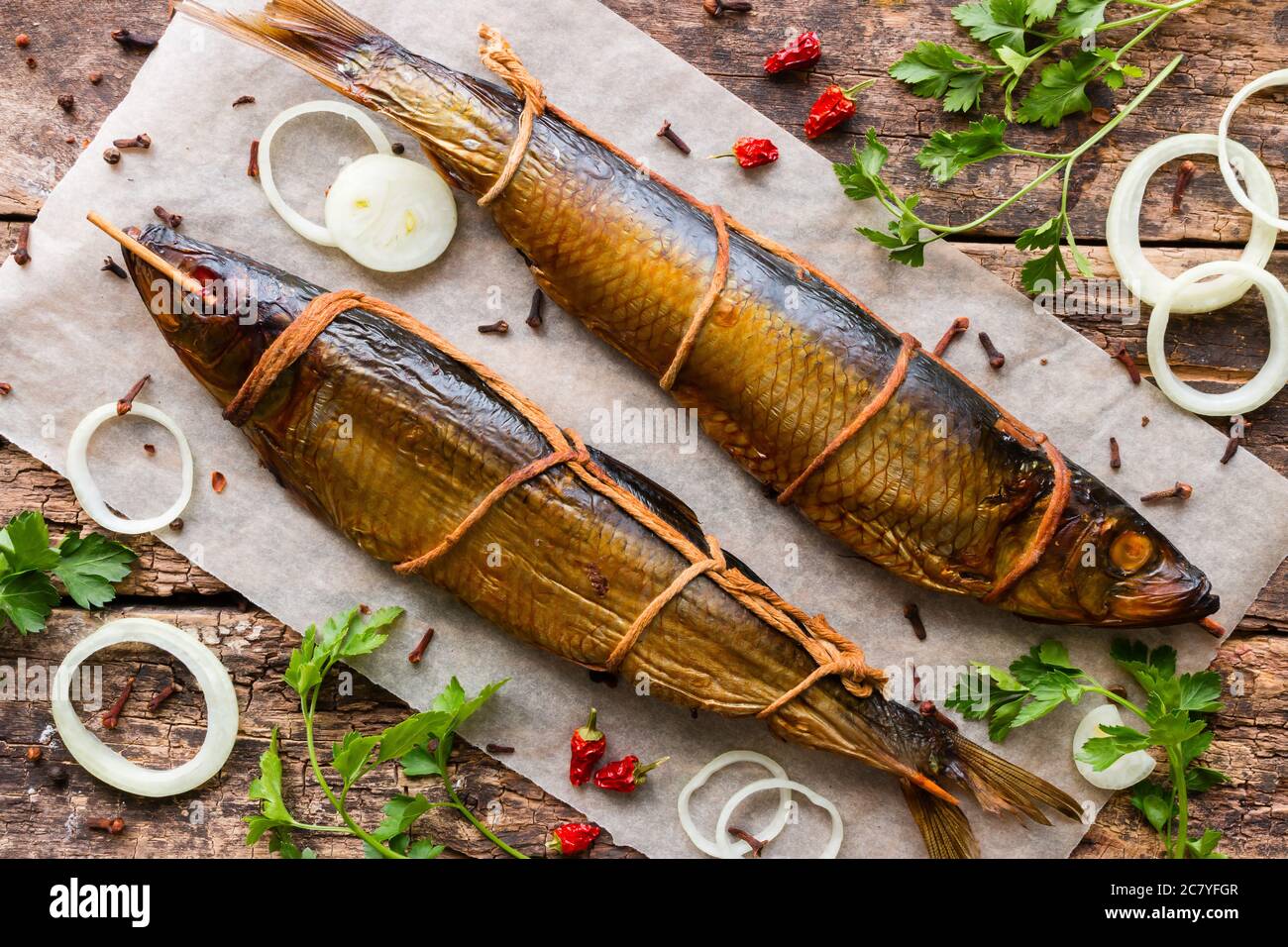Geräucherter Hering auf Holzgrund mit Gemüse und Gewürzen Stockfoto