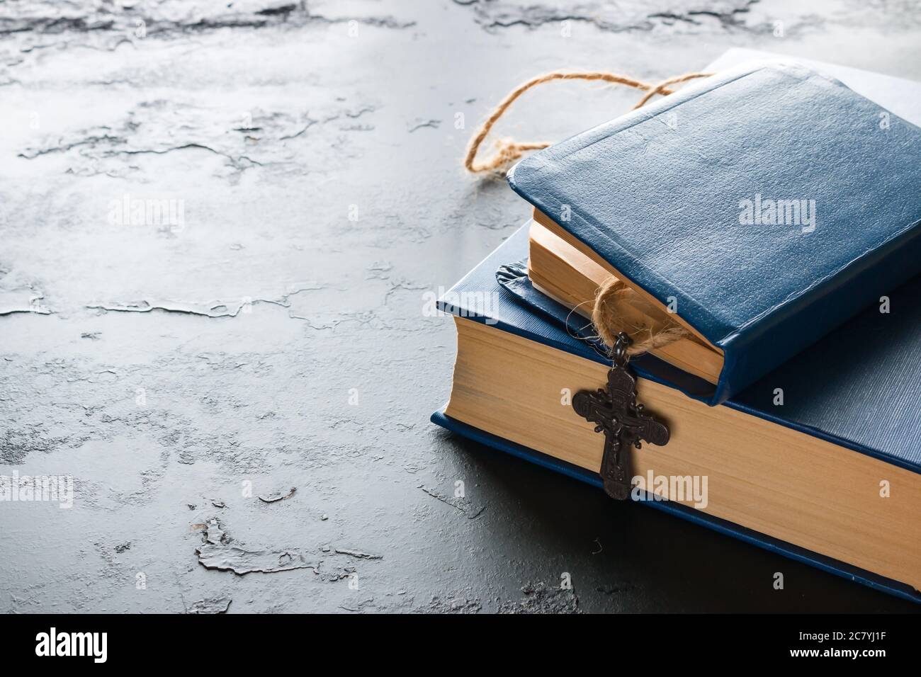 Bücher der Bibel und des christlichen Kreuzes auf schwarzem Hintergrund mit Platz für Text Stockfoto