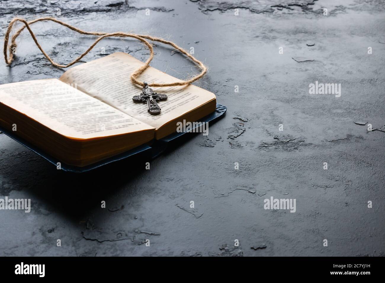 Bibel und christliches Kreuz auf schwarzem Hintergrund mit Platz für Text Stockfoto