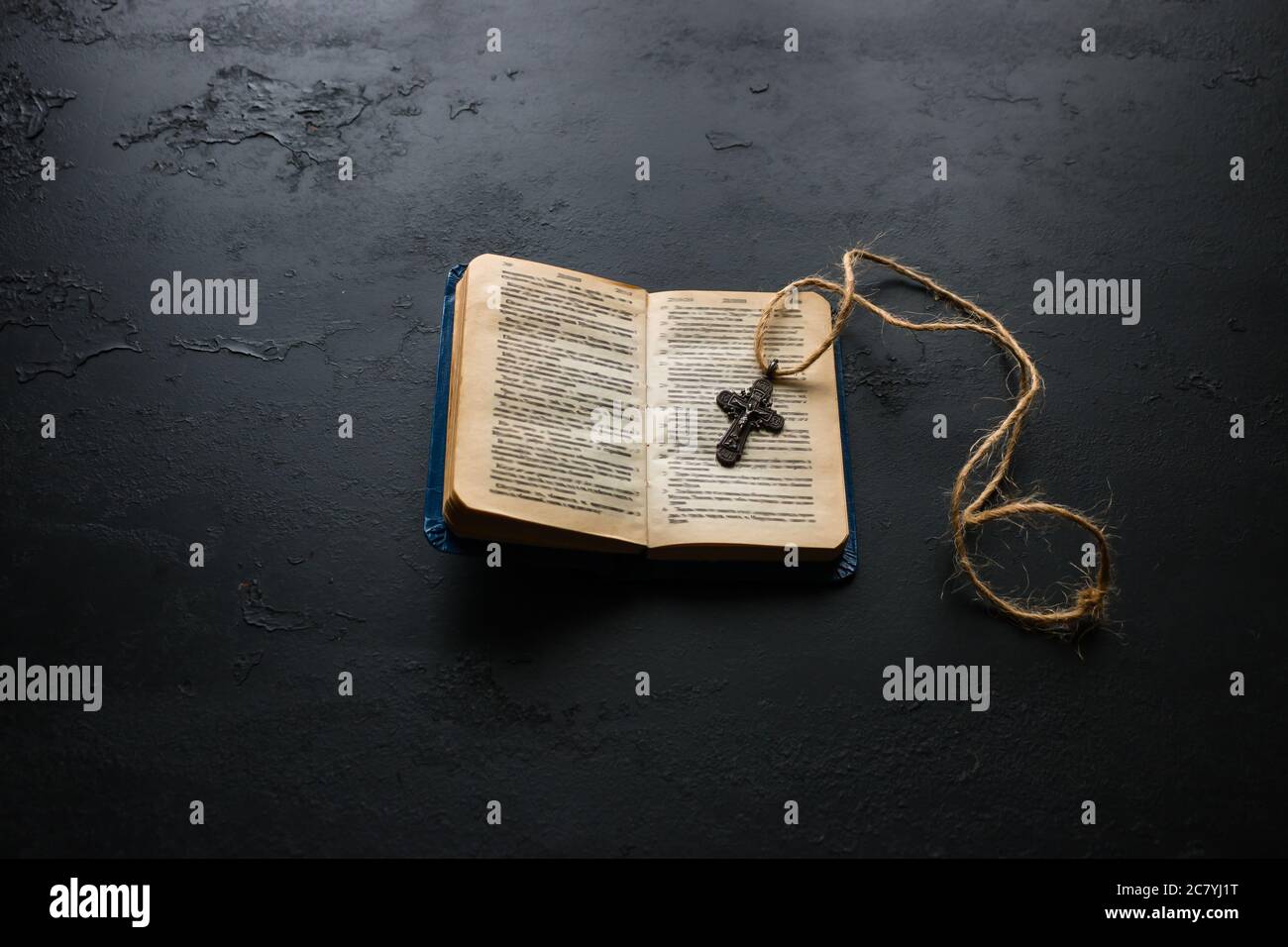 Offene bibel und christliches Kreuz auf schwarzem Hintergrund Stockfoto