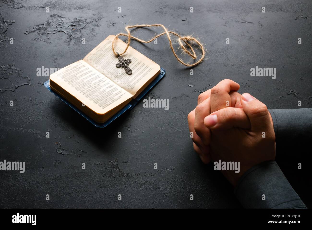 Der Mann betet nahe der bibel und dem christlichen Kreuz Stockfoto