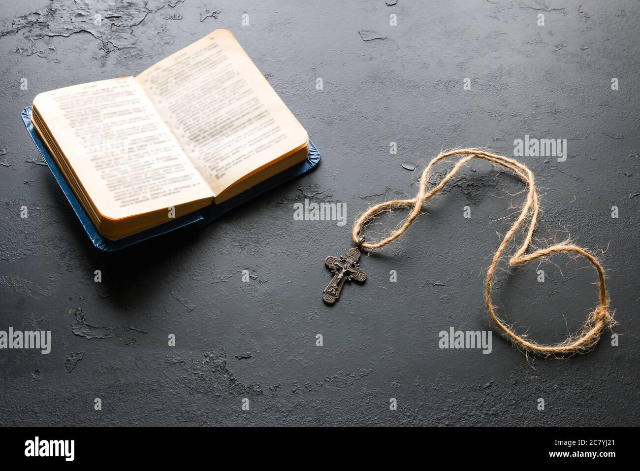 Bibel und christliches Kreuz auf schwarzem Hintergrund Stockfoto