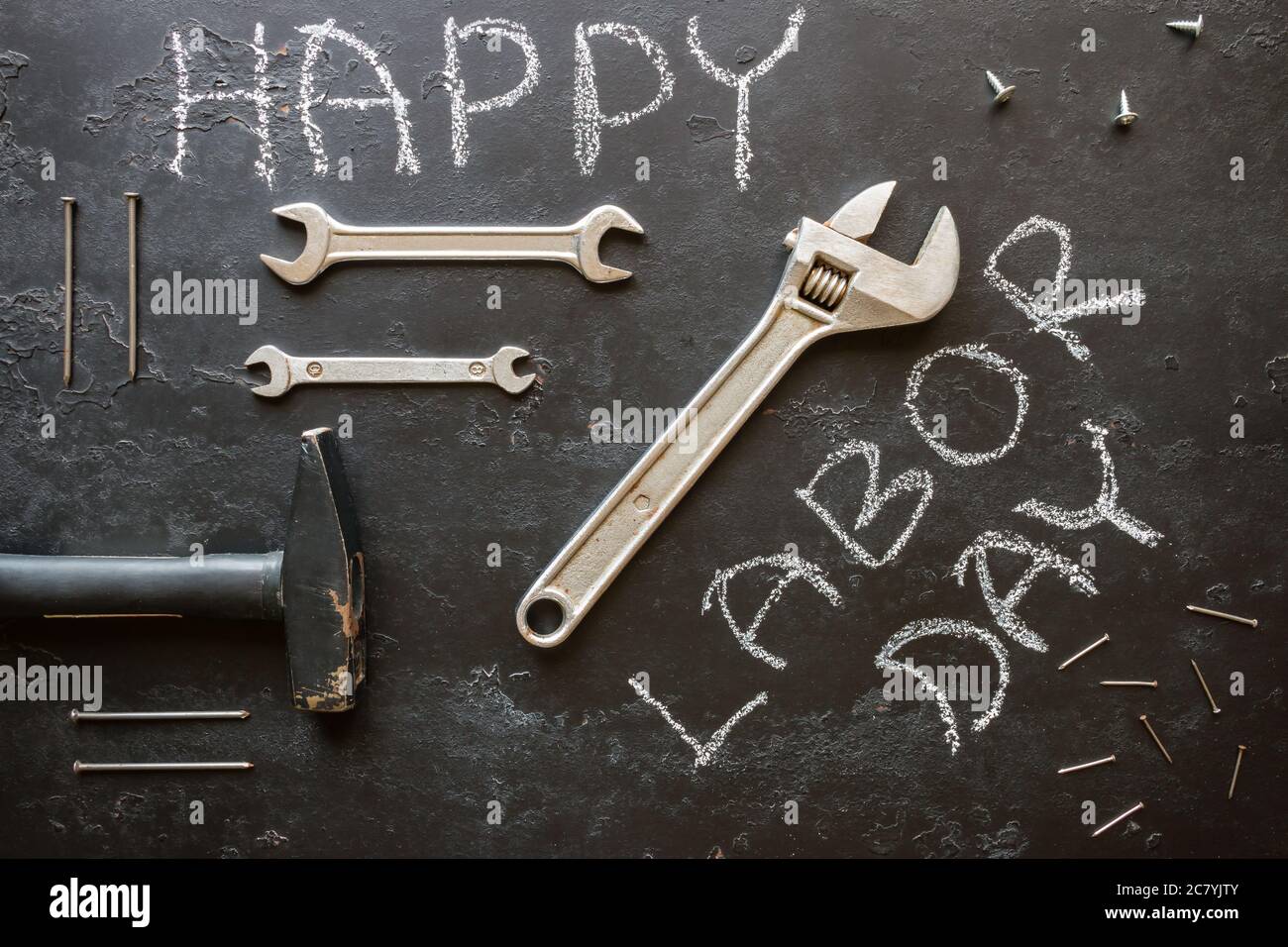 Bauwerkzeuge und Inschrift glücklicher Arbeitstag auf schwarzem Hintergrund Stockfoto