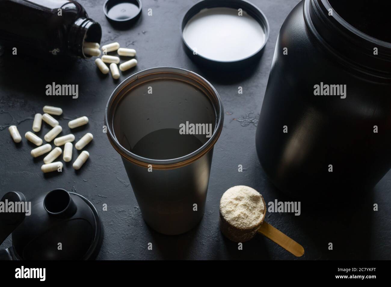 Shaker, Protein, Kreatin und andere Sportergänzungen auf schwarzem Hintergrund Stockfoto