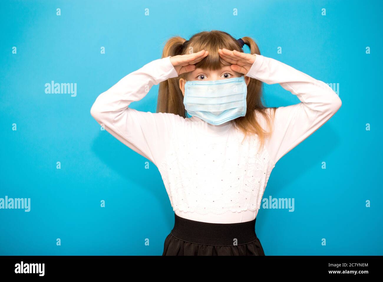 Happy kleines Mädchen in schützende medizinische Maske Blick in gute Zukunft isoliert auf blauem Hintergrund. Sieg über Coronavirus. Ende der COVID-19 Pandemie-Crisi Stockfoto