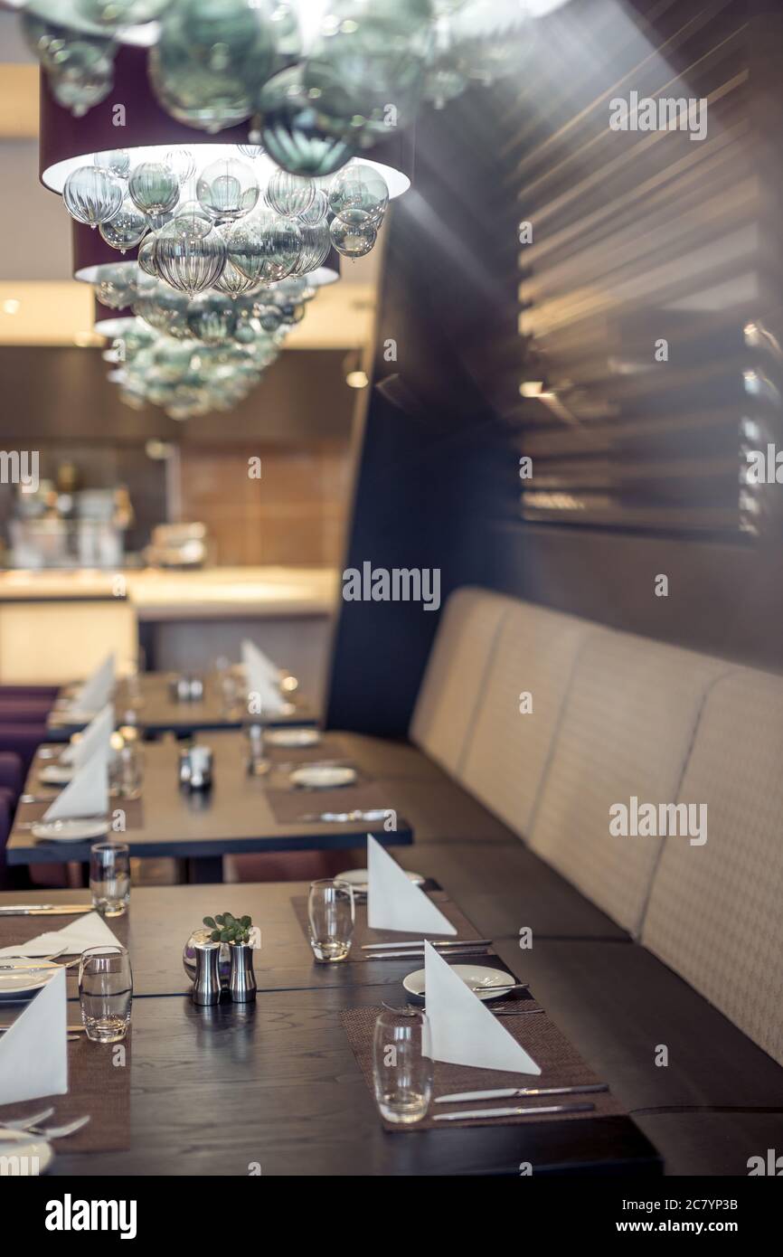 Halb beleuchtete Halle im Loft-Stil in einem mexikanischen Restaurant mit offener Küche im Hintergrund. Vor der Küche gibt es Holztische mit mu Stockfoto
