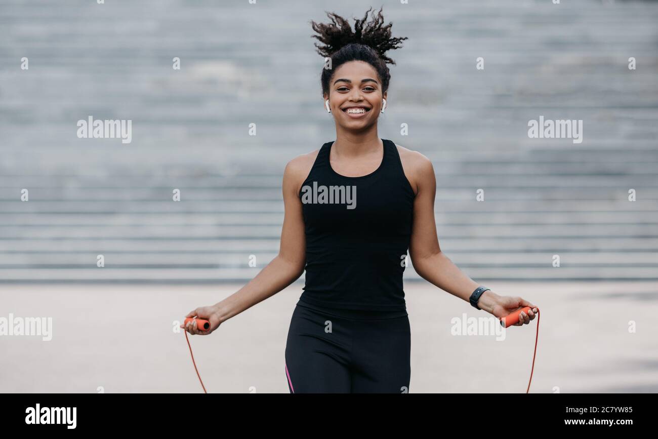 Mädchen in Sportbekleidung mit Fitness-Tracker-Training mit Springseil Stockfoto