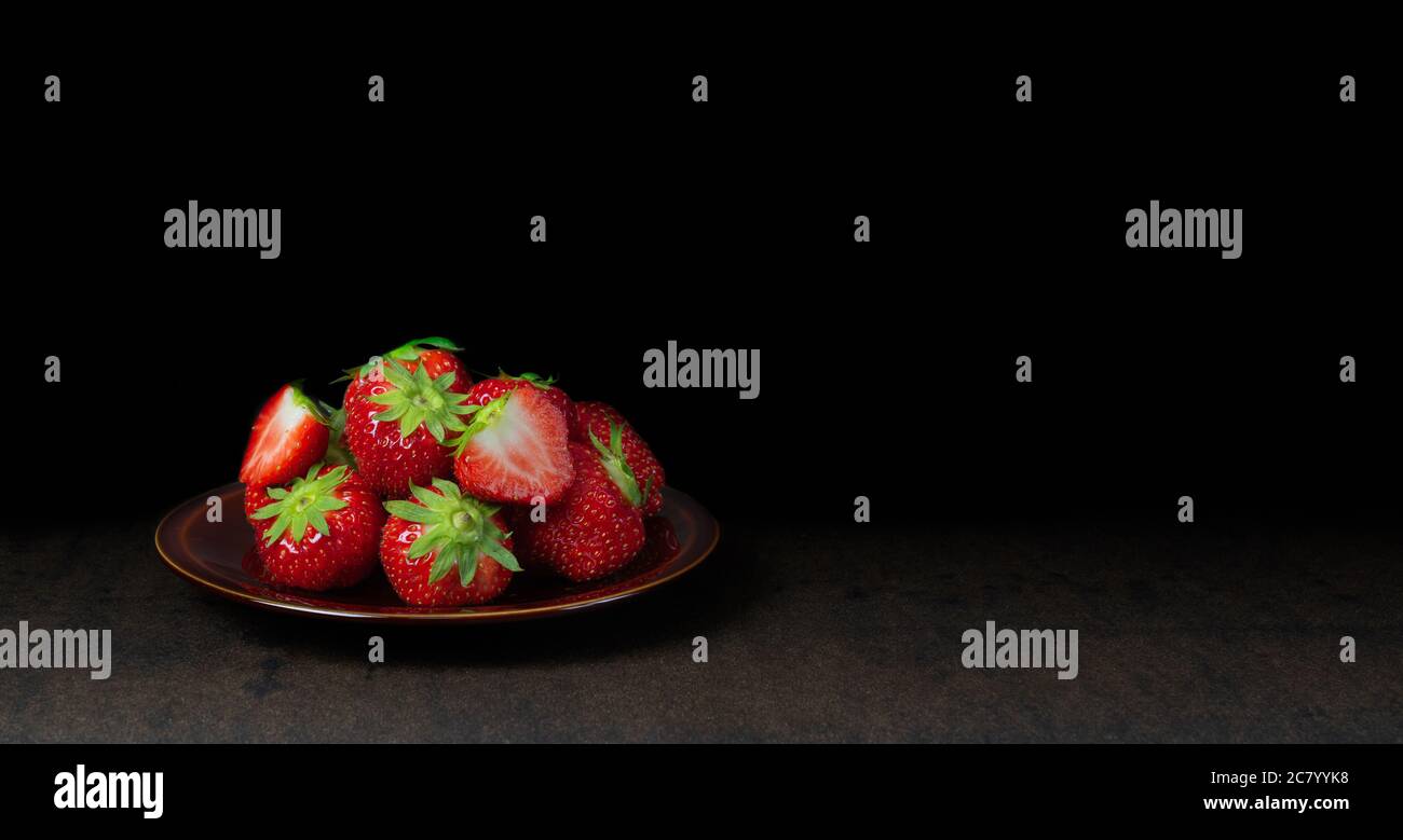 Erdbeerfrucht in einer Schüssel vor dunklem Hintergrund. Stockfoto
