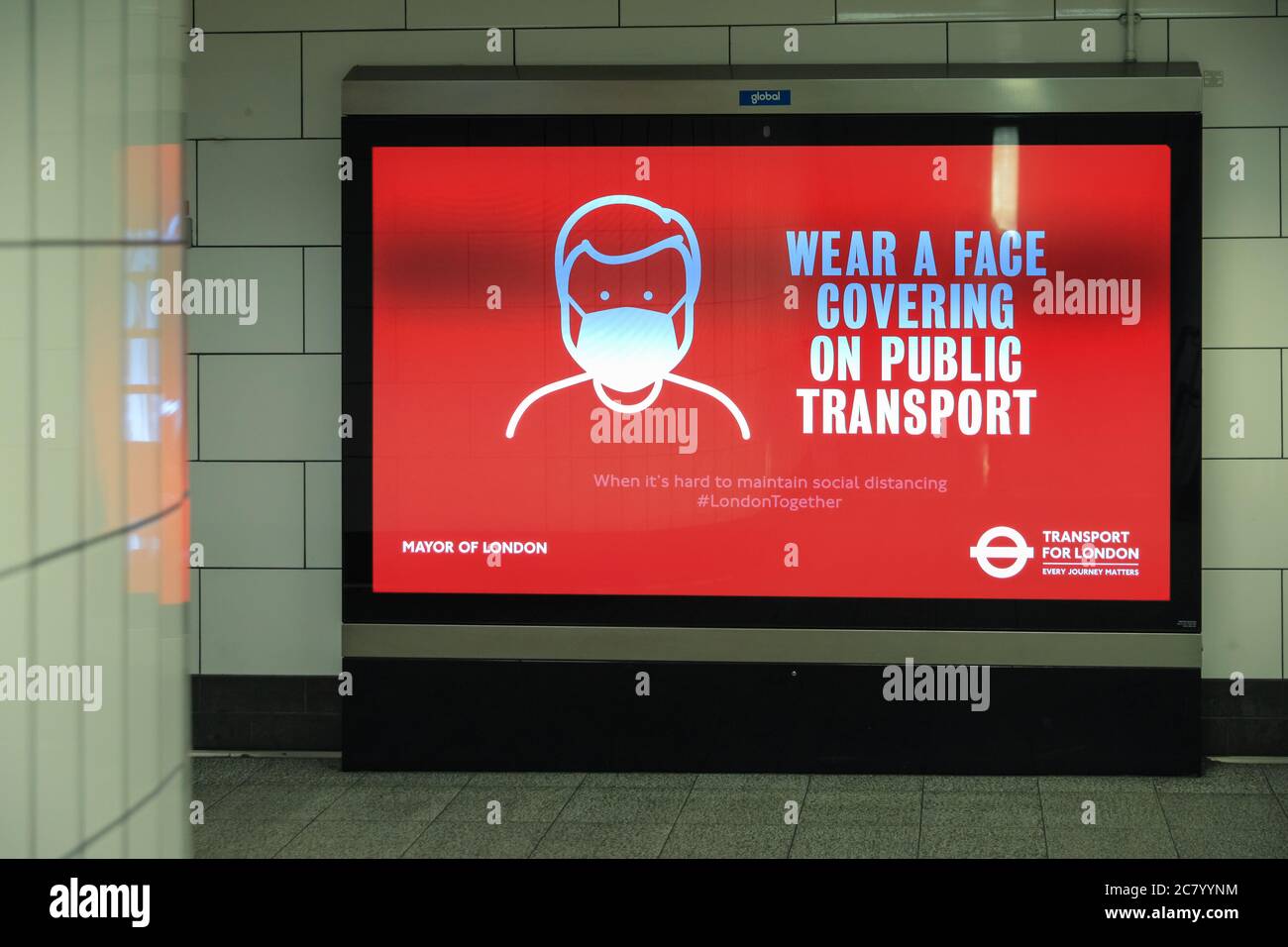 Plakatwand, die rät, "eine Gesichtsbedeckung auf öffentlichen Verkehrsmitteln zu tragen" bezüglich obligatorischer Gesichtsmasken, U-Bahn-Stsation, London, England, Großbritannien Stockfoto