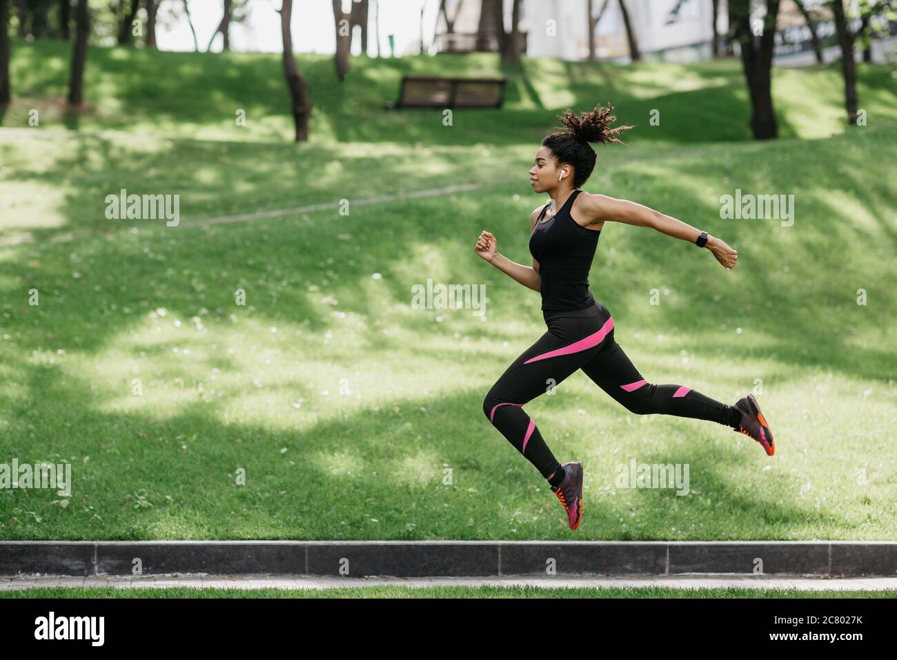 Springen und Laufen im Freien in der Natur. Mädchen in Sport Uniform gefroren in der Luft Stockfoto