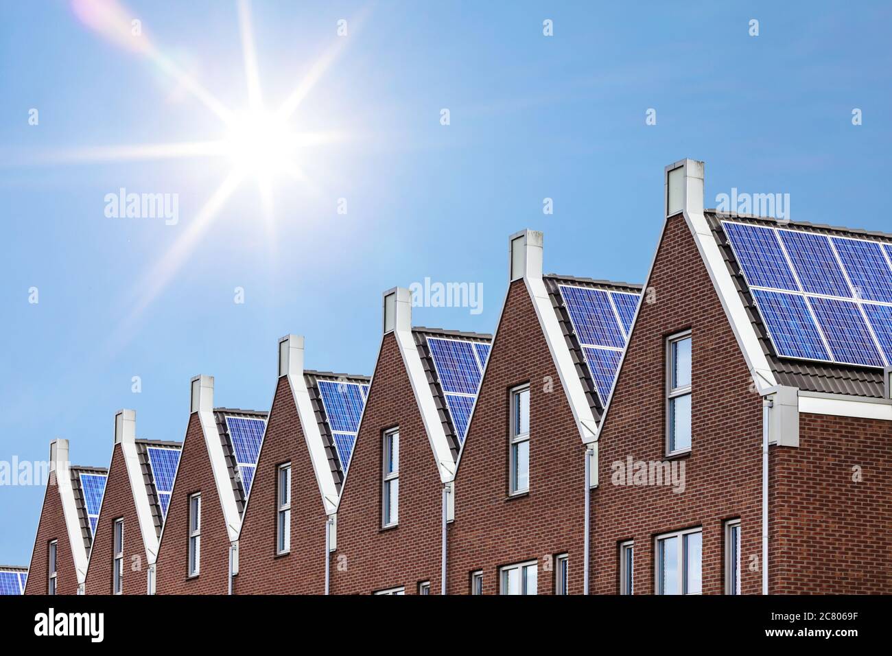 Neu errichtete Häuser mit Solarzellen auf dem Dach gegen einen sonnigen Himmel Stockfoto