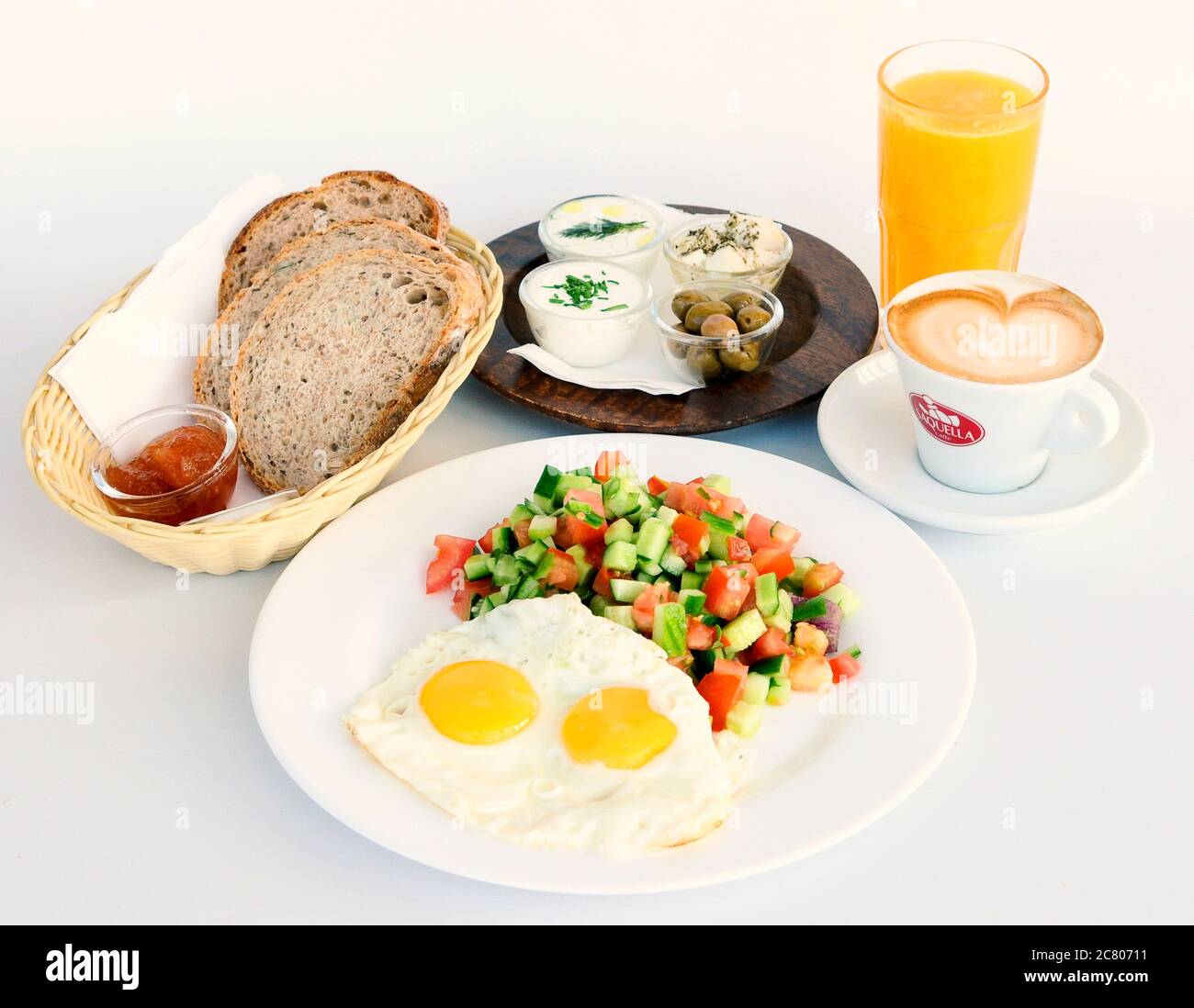 Israelisches Frühstück mit zwei Spiegeleiern, Salat, Brot, Butter, Käse, Orangensaft und Kaffee Stockfoto