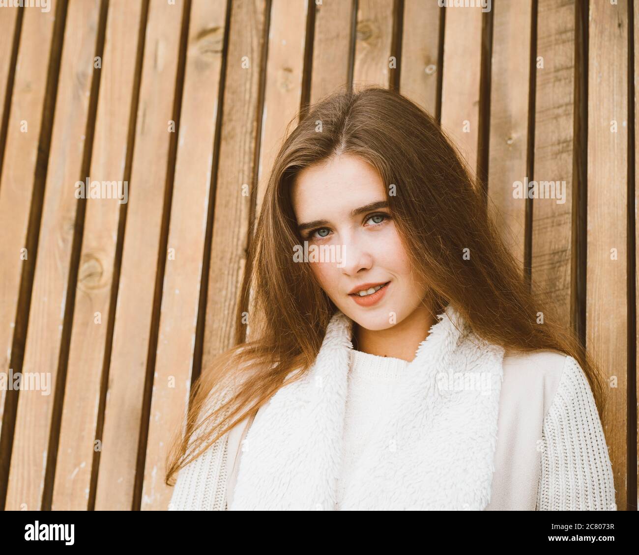 Nahaufnahme Porträt von schönen jungen Mädchen mit langen braunen Haaren auf Holzhintergrund von Planken, Winter oder Herbst im Freien Fotoshooting mit attraktiven Stockfoto