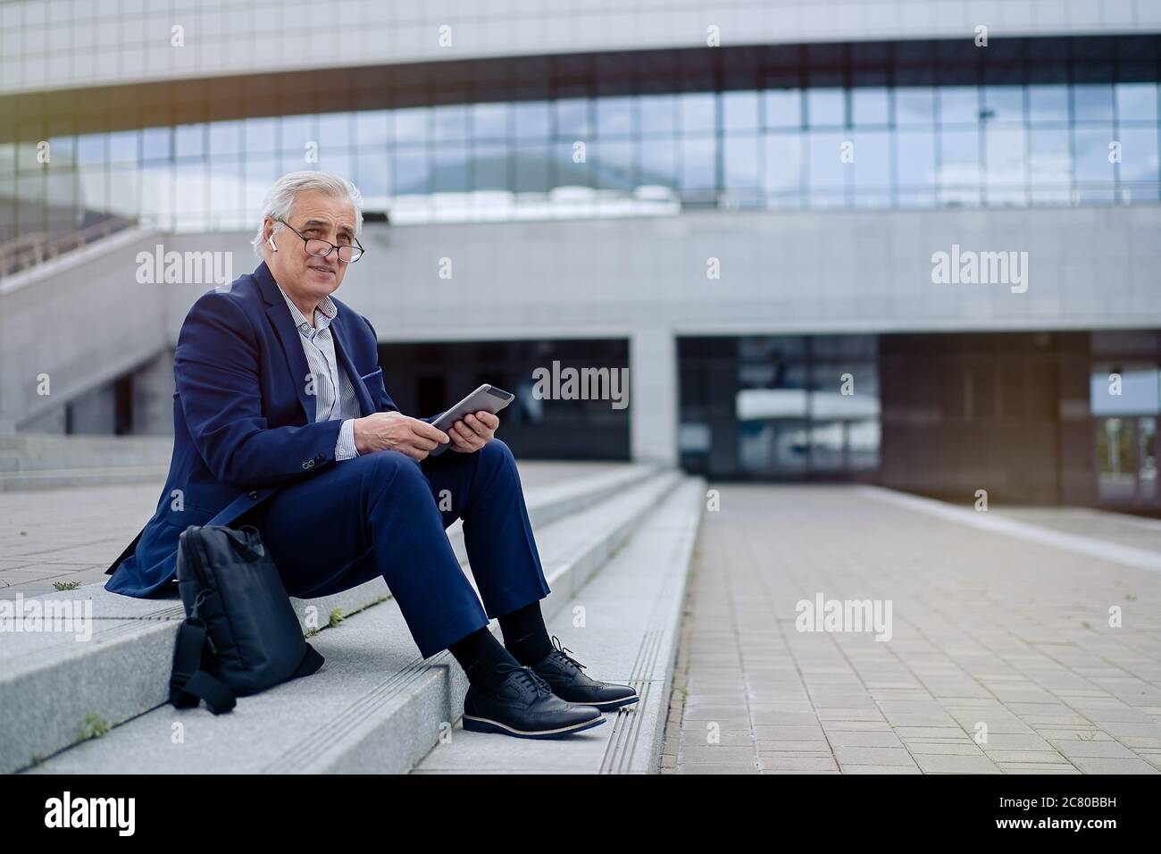 Ein Geschäftsmann, der ein Tablet in einer Stadt benutzt Stockfoto