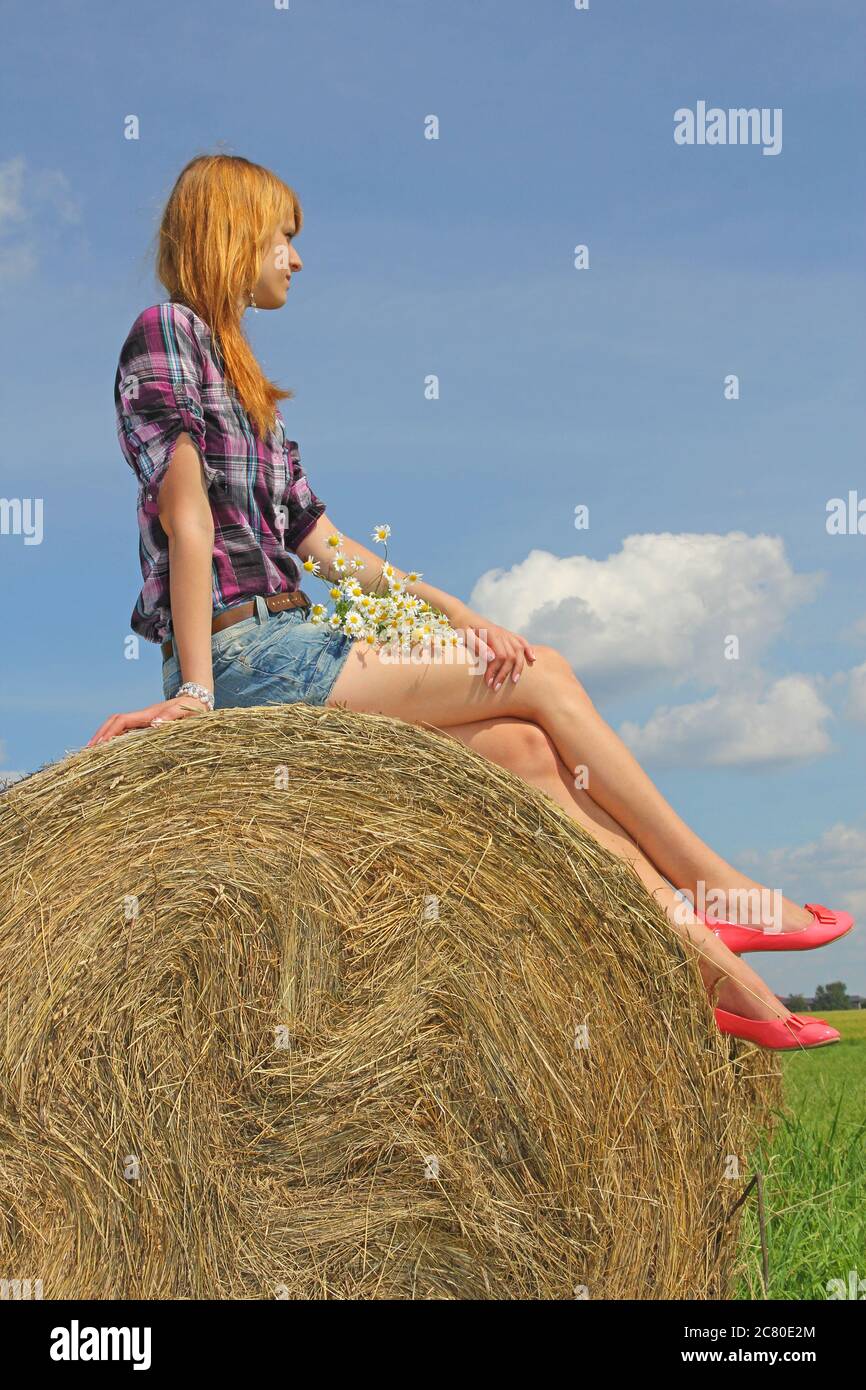 Attraktive Mädchen auf Strohballen sitzen Stockfoto