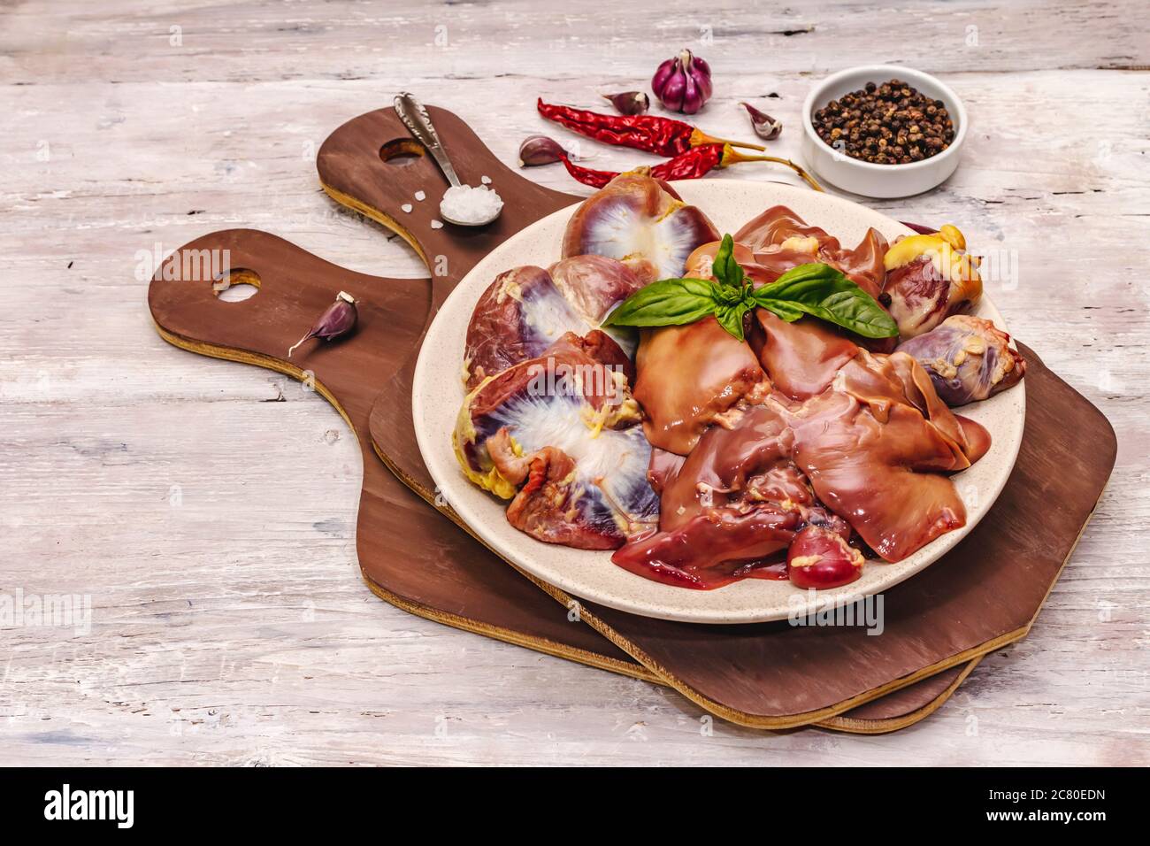 Frische rohe Hühnerfleisch: Herz, Leber, Magen. Trockene Gewürze, Meersalz, Chili. Weiße Holzbretter Hintergrund, kopieren Raum Stockfoto