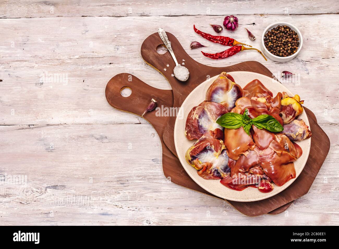 Frische rohe Hühnerfleisch: Herz, Leber, Magen. Trockene Gewürze, Meersalz, Chili. Weiße Holzbretter Hintergrund, Draufsicht Stockfoto