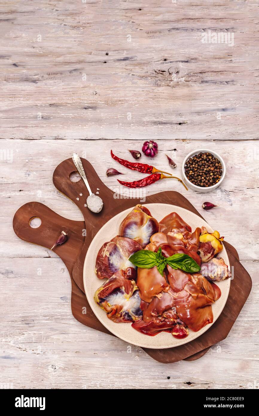 Frische rohe Hühnerfleisch: Herz, Leber, Magen. Trockene Gewürze, Meersalz, Chili. Weiße Holzbretter Hintergrund, Draufsicht Stockfoto