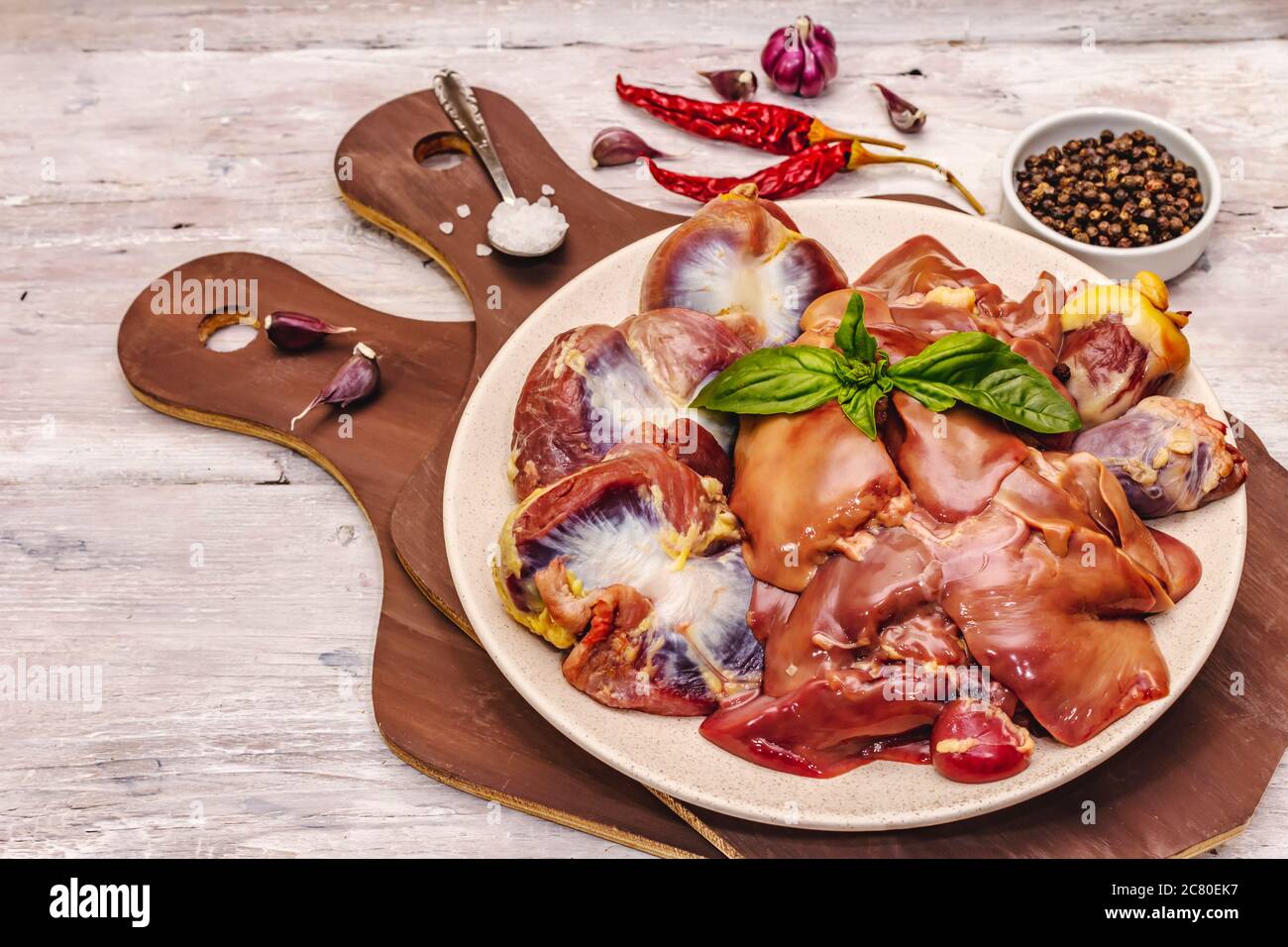 Frische rohe Hühnerfleisch: Herz, Leber, Magen. Trockene Gewürze, Meersalz, Chili. Weiße Holzbretter Hintergrund, kopieren Raum Stockfoto