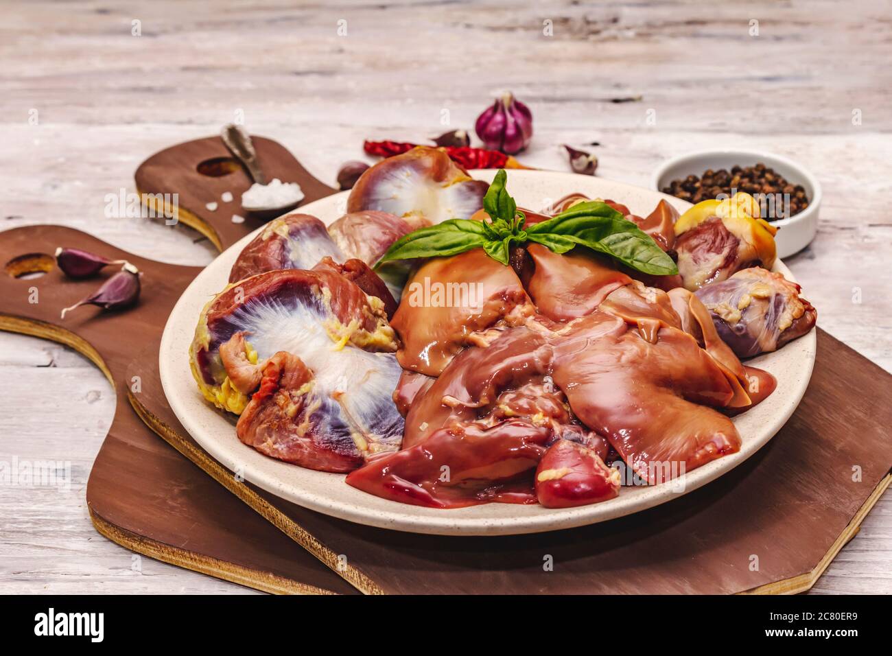 Frische rohe Hühnerfleisch: Herz, Leber, Magen. Trockene Gewürze, Meersalz, Chili. Weiße Holzbretter Hintergrund, Nahaufnahme Stockfoto