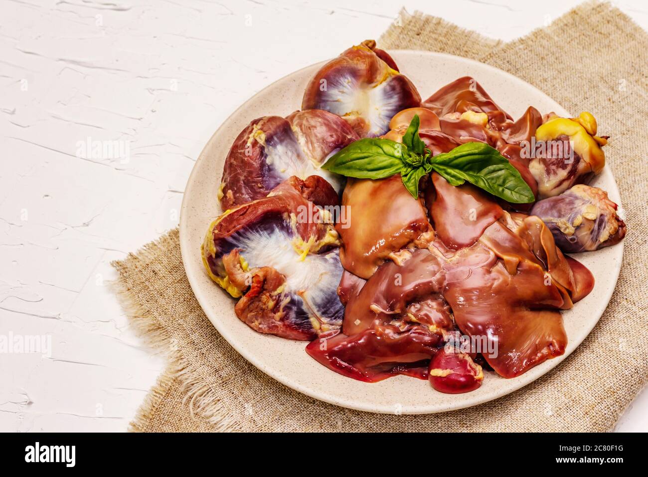 Frische rohe Hühnerfleisch: Herz, Leber, Magen. Trockene Gewürze, Meersalz, Chili. Weißer Kitt Hintergrund, Kopierraum Stockfoto