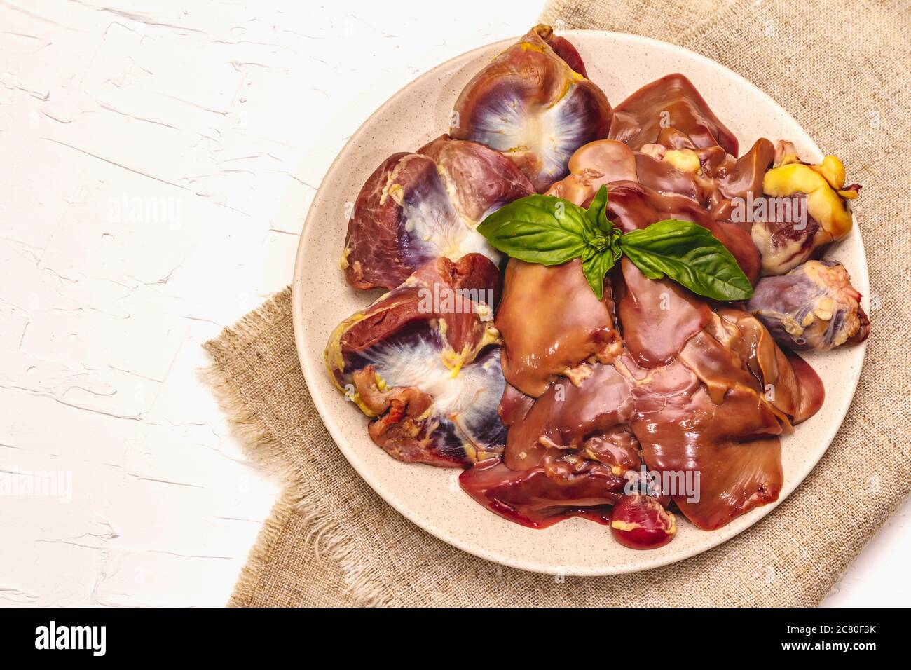 Frische rohe Hühnerfleisch: Herz, Leber, Magen. Trockene Gewürze, Meersalz, Chili. Weißer Kitt Hintergrund, Draufsicht Stockfoto