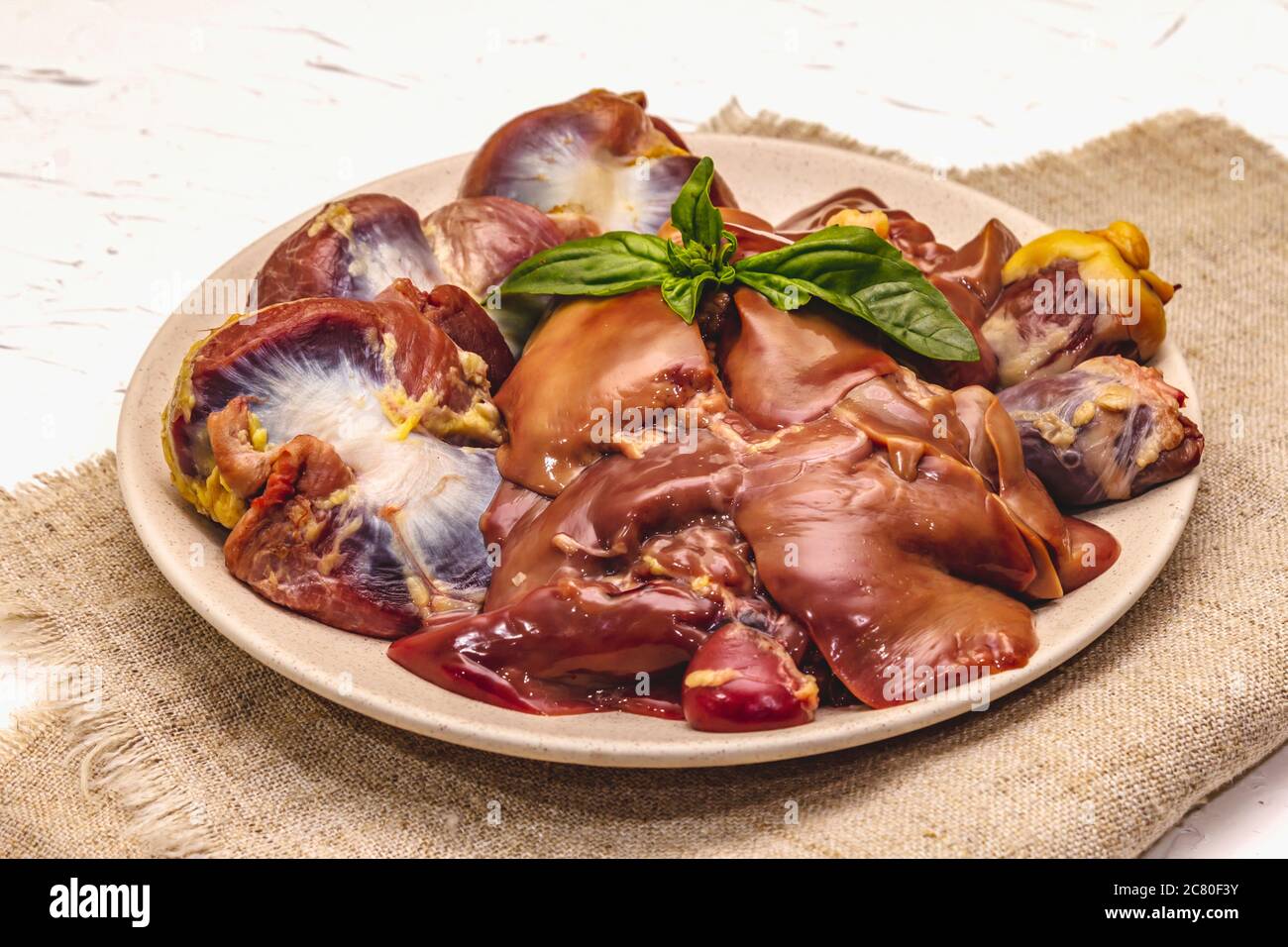 Frische rohe Hühnerfleisch: Herz, Leber, Magen. Trockene Gewürze, Meersalz, Chili. Weißer Kitt Hintergrund, Nahaufnahme Stockfoto