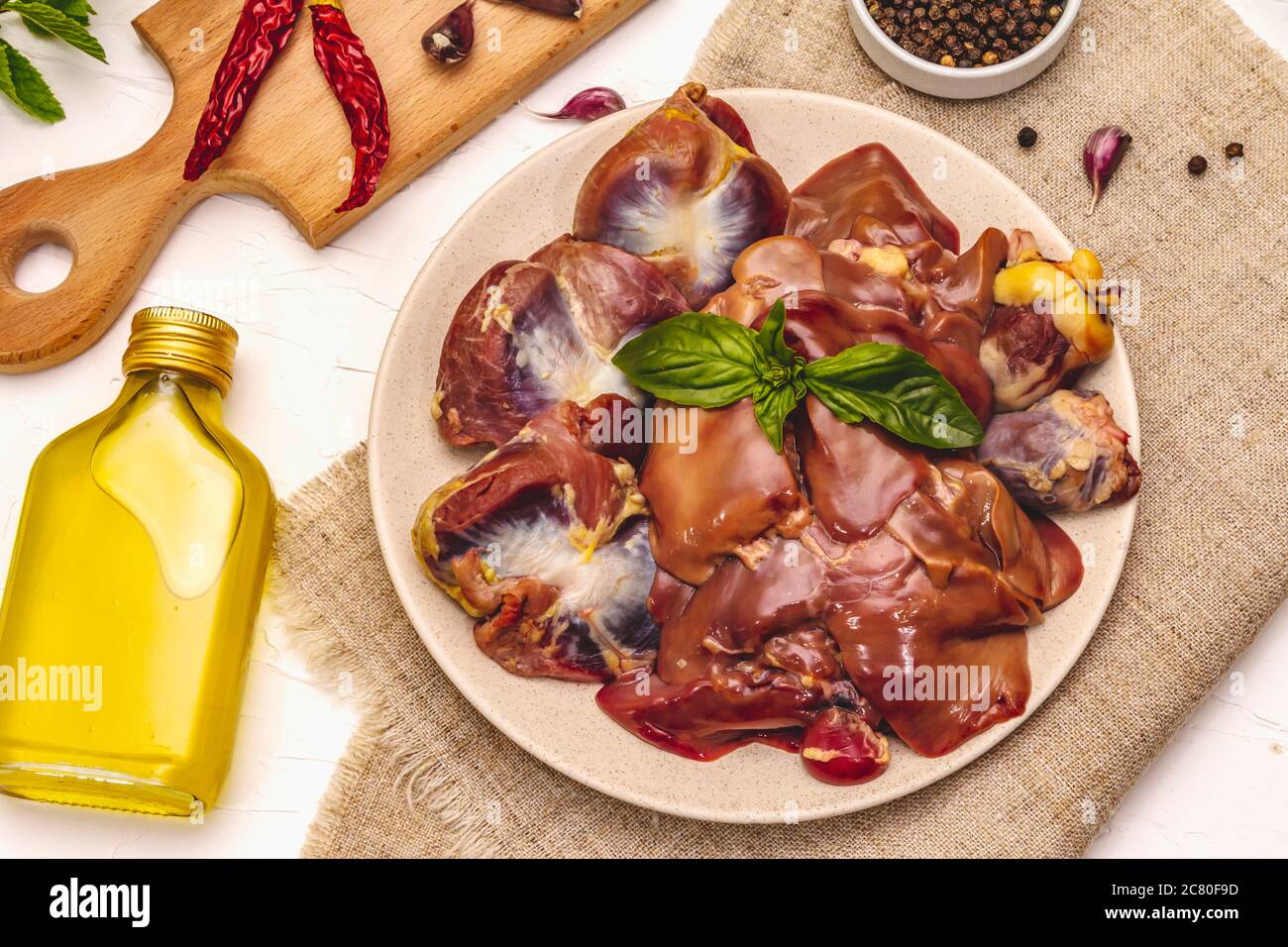 Frische rohe Hühnerfleisch: Herz, Leber, Magen. Trockene Gewürze, Meersalz, Chili, Olivenöl, frische Minze. Weißer Kitt Hintergrund, Draufsicht Stockfoto