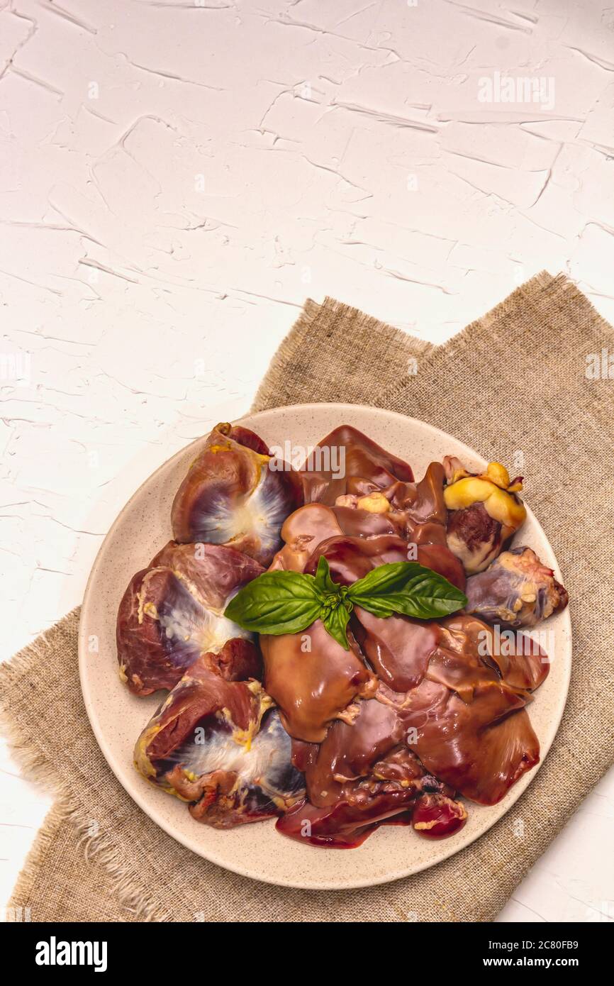 Frische rohe Hühnerfleisch: Herz, Leber, Magen. Trockene Gewürze, Meersalz, Chili. Weißer Kitt Hintergrund, Draufsicht Stockfoto