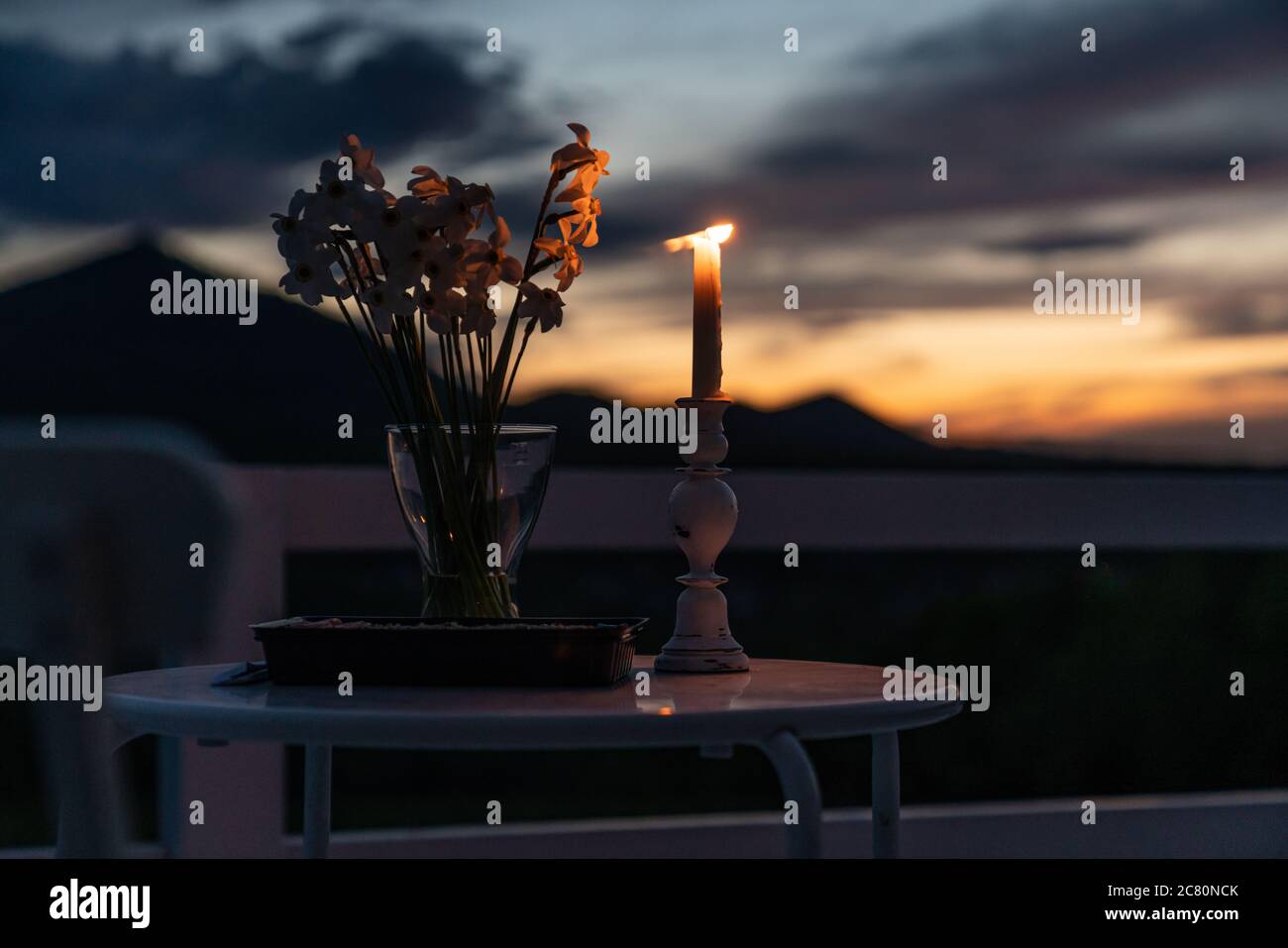 Minimalistischer Tisch für ein romantisches Abendessen im Urlaub, Holztisch mit Blumen und weißen Kerzen. Selektiver Fokus Stockfoto