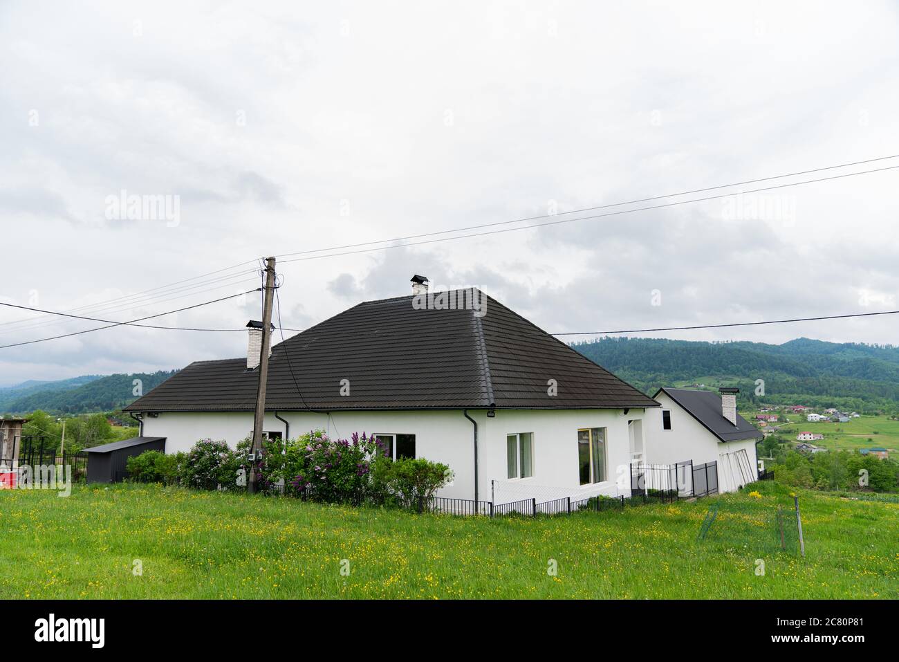 Weißes Holzhaus mit dunklem Dach in der Nähe von schönen Bergen Stockfoto